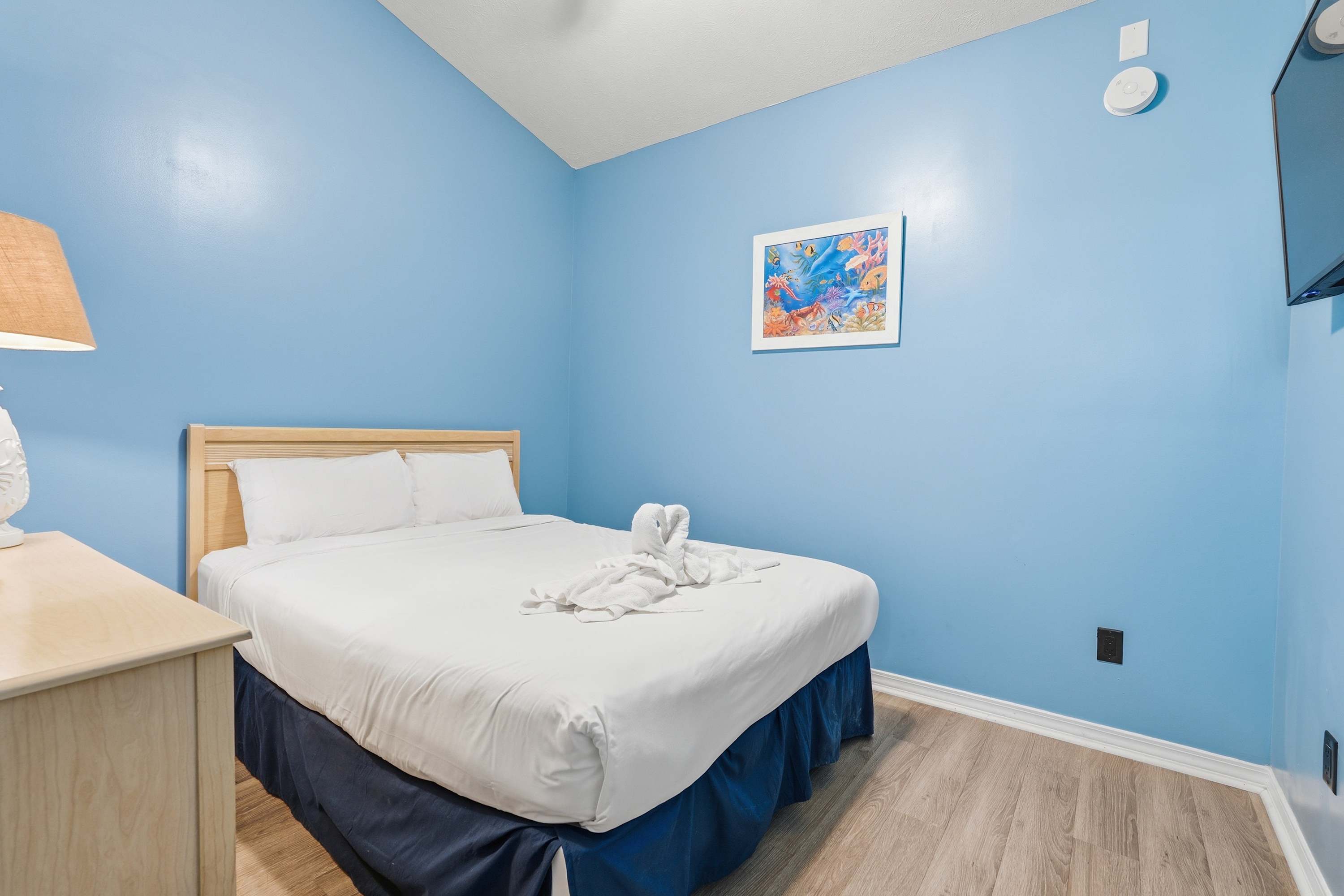 135 Grande Island Blvd – Cozy bedroom with a blue accent wall, queen bed, and wall-mounted TV.