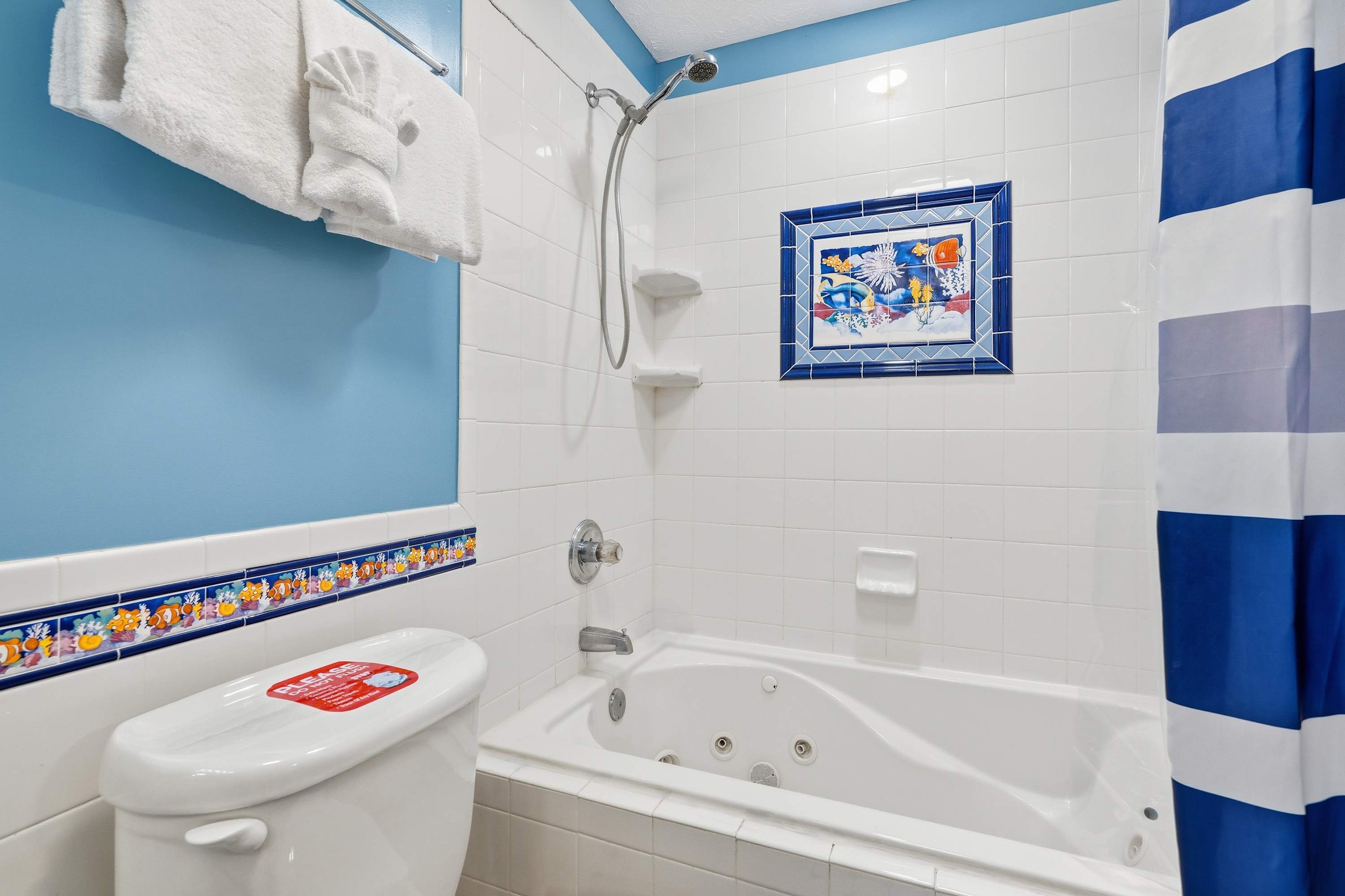 135 Grande Island Blvd – Bathroom with a shower, jetted tub, colorful tile accents, and blue walls.