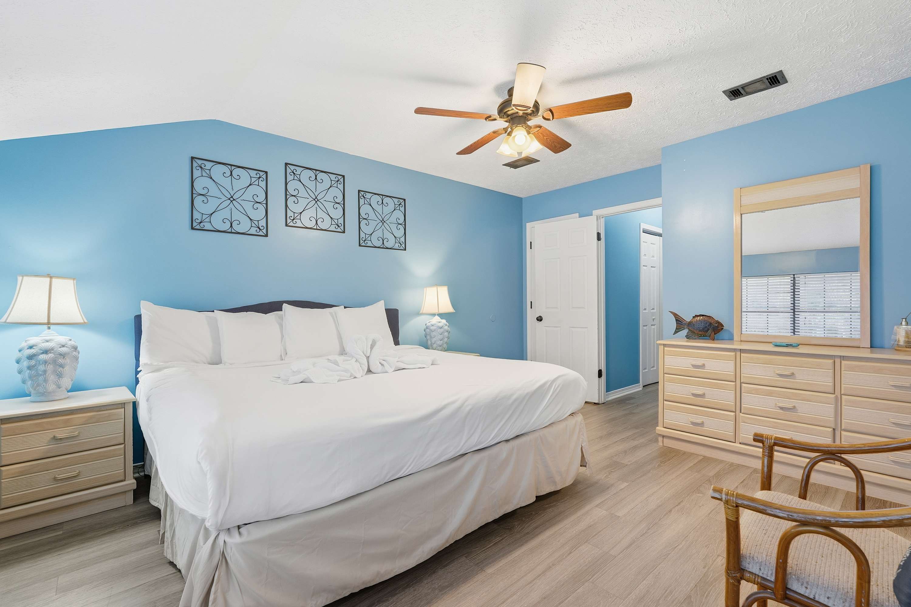 135 Grande Island Blvd – Bedroom with a large bed, blue walls, dresser, mirror, and ceiling fan.