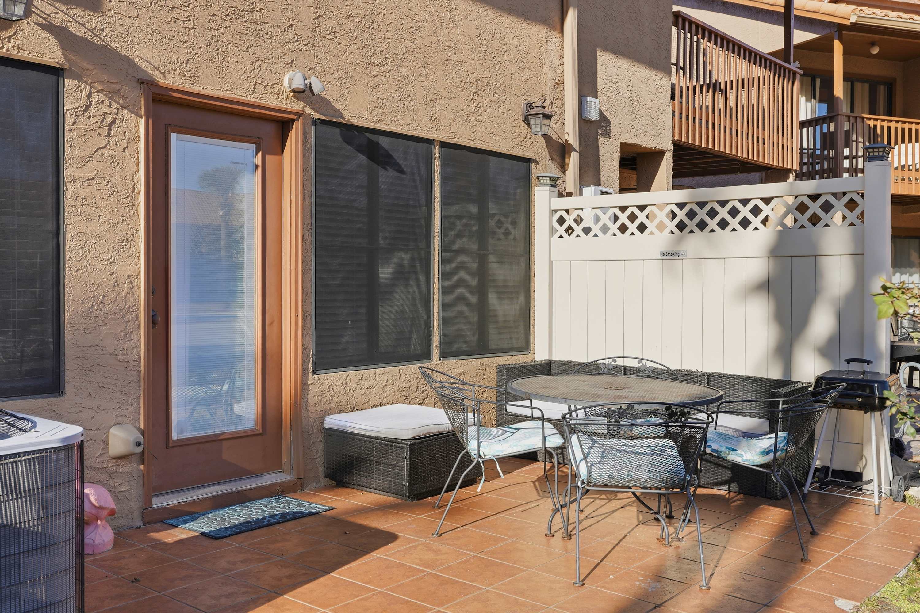 135 Grande Island Blvd – Outdoor patio with dining table, chairs, and grill; adjacent to entrance and fenced area.