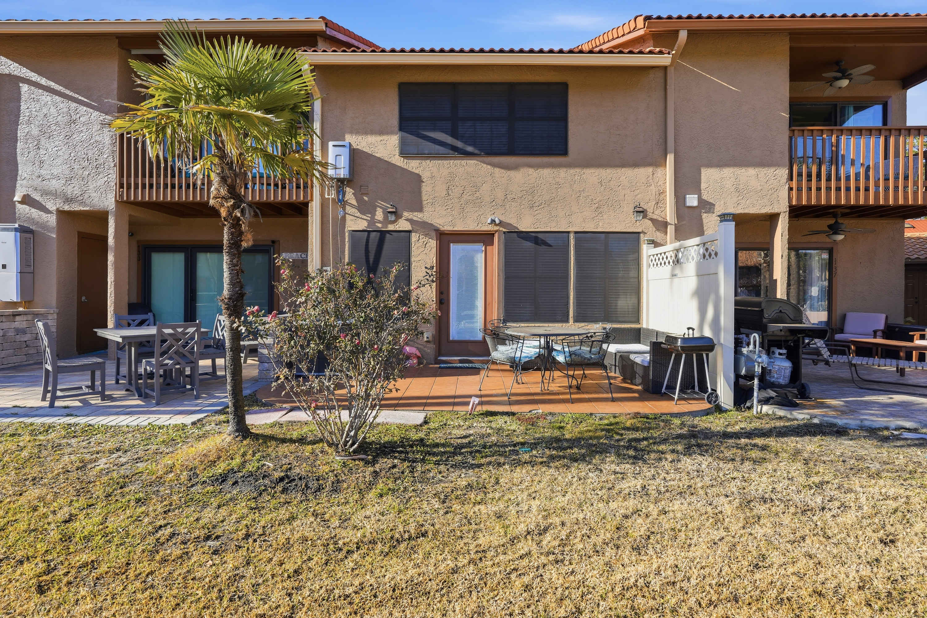 135 Grande Island Blvd – Exterior view of a vacation rental with patio seating, grill, and palm tree.