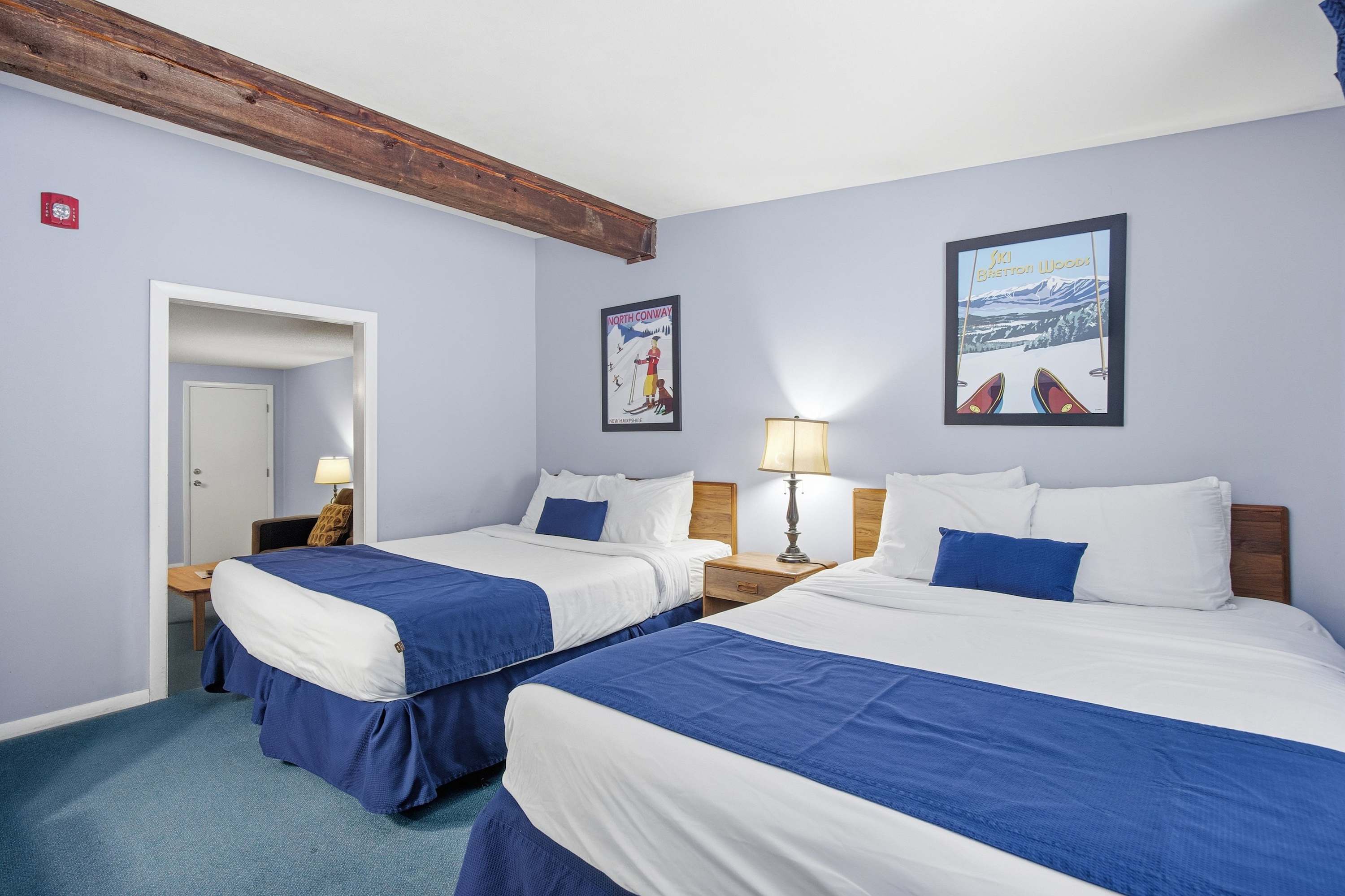 The bedroom includes a pair of plush queen beds & a wall-mounted TV​