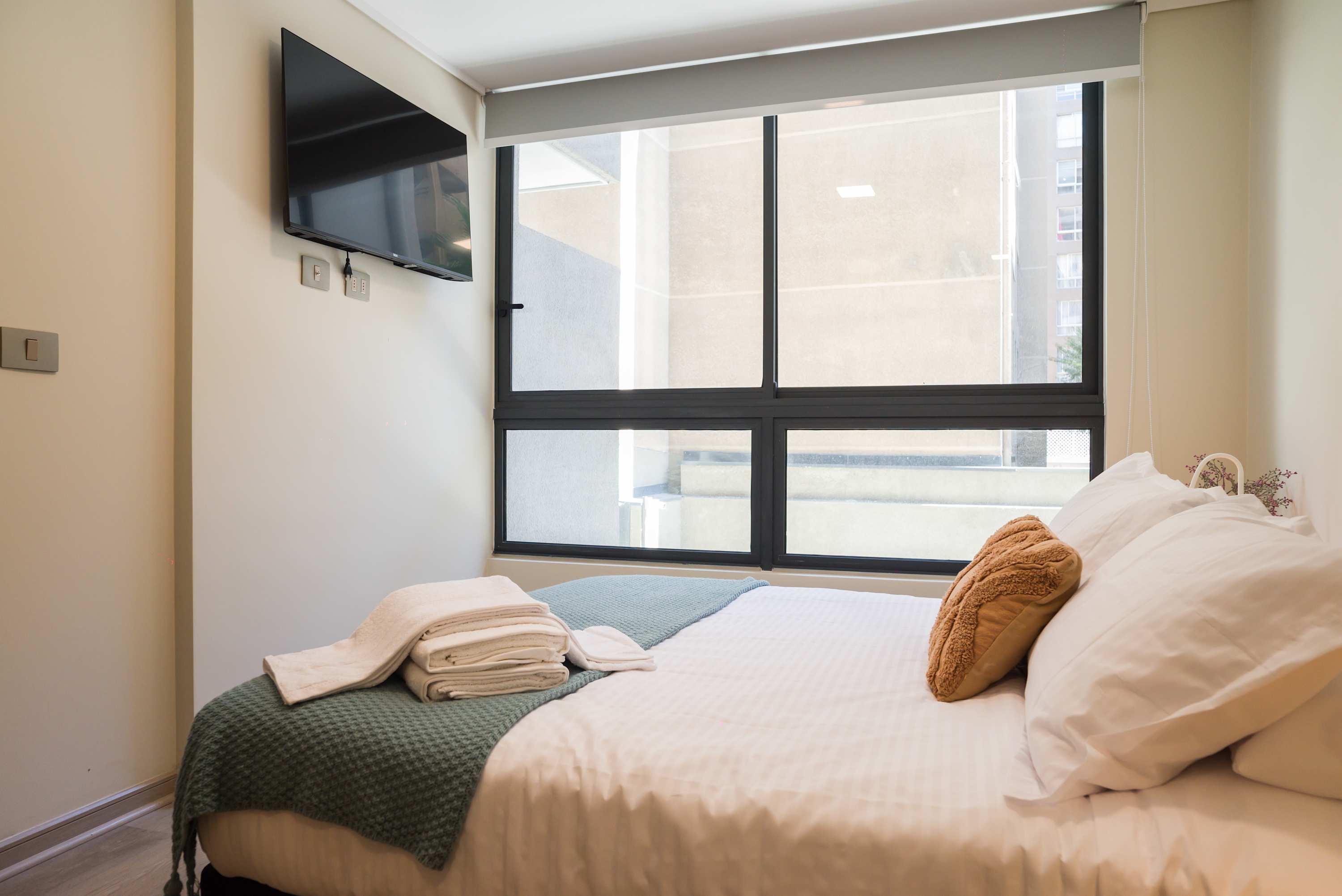Relax in this cozy bedroom with natural light and modern amenities, perfect for unwinding after a day in the city.