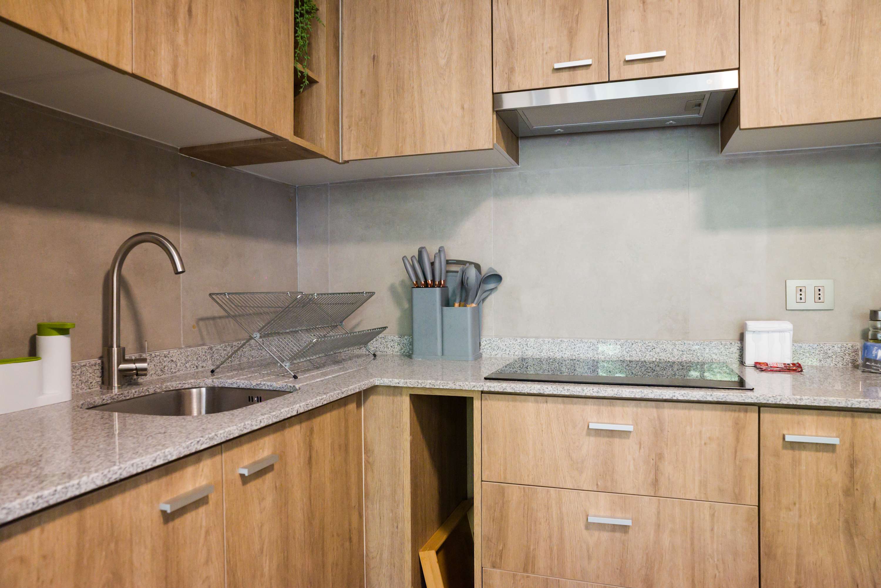 Private kitchen with warm wood cabinetry, granite counters, stainless-steel sink, and a built-in cooktop for convenient meal preparation.