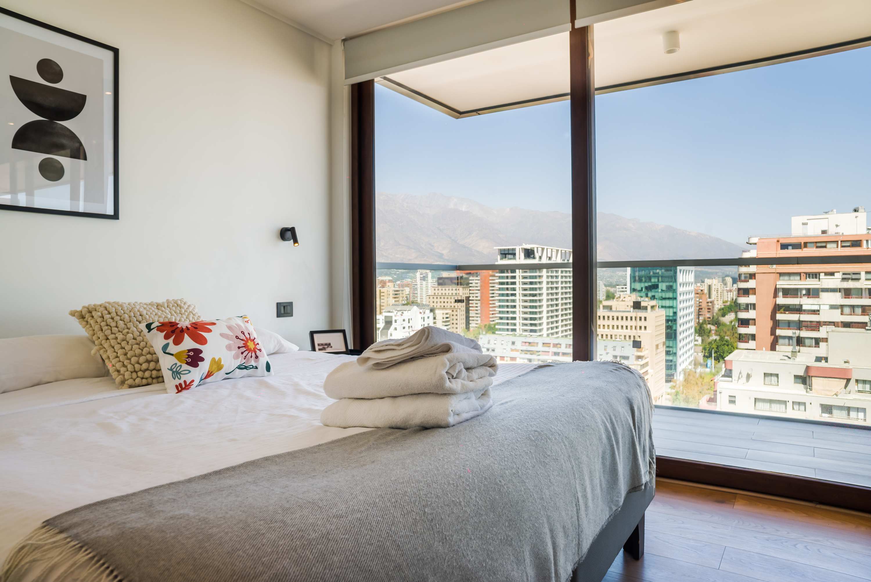 Relax in a cozy bedroom with breathtaking city and mountain views, perfect for unwinding after a day of exploring.