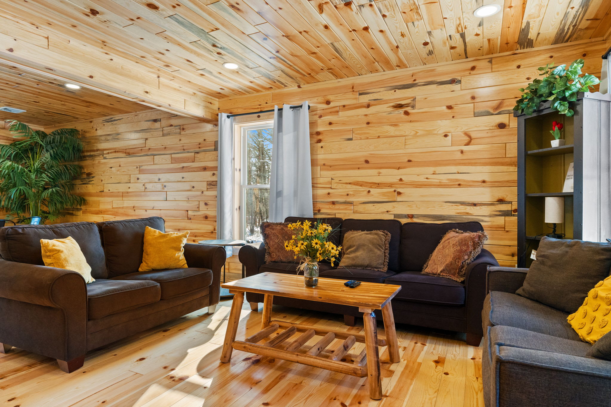 Colorful throw pillows and fresh flowers add warmth to the cabin living room