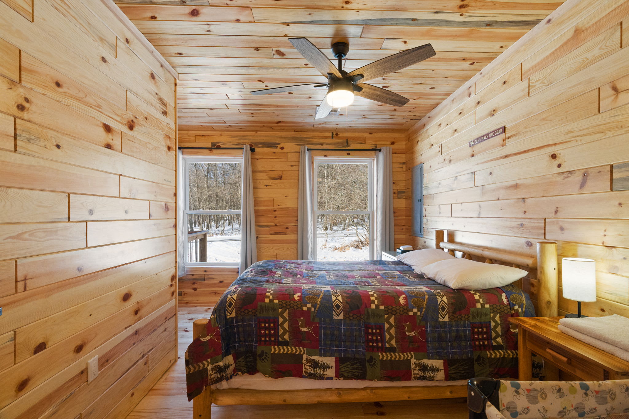 A cabin-themed quilt and warm log walls make this bedroom feel like a true retreat