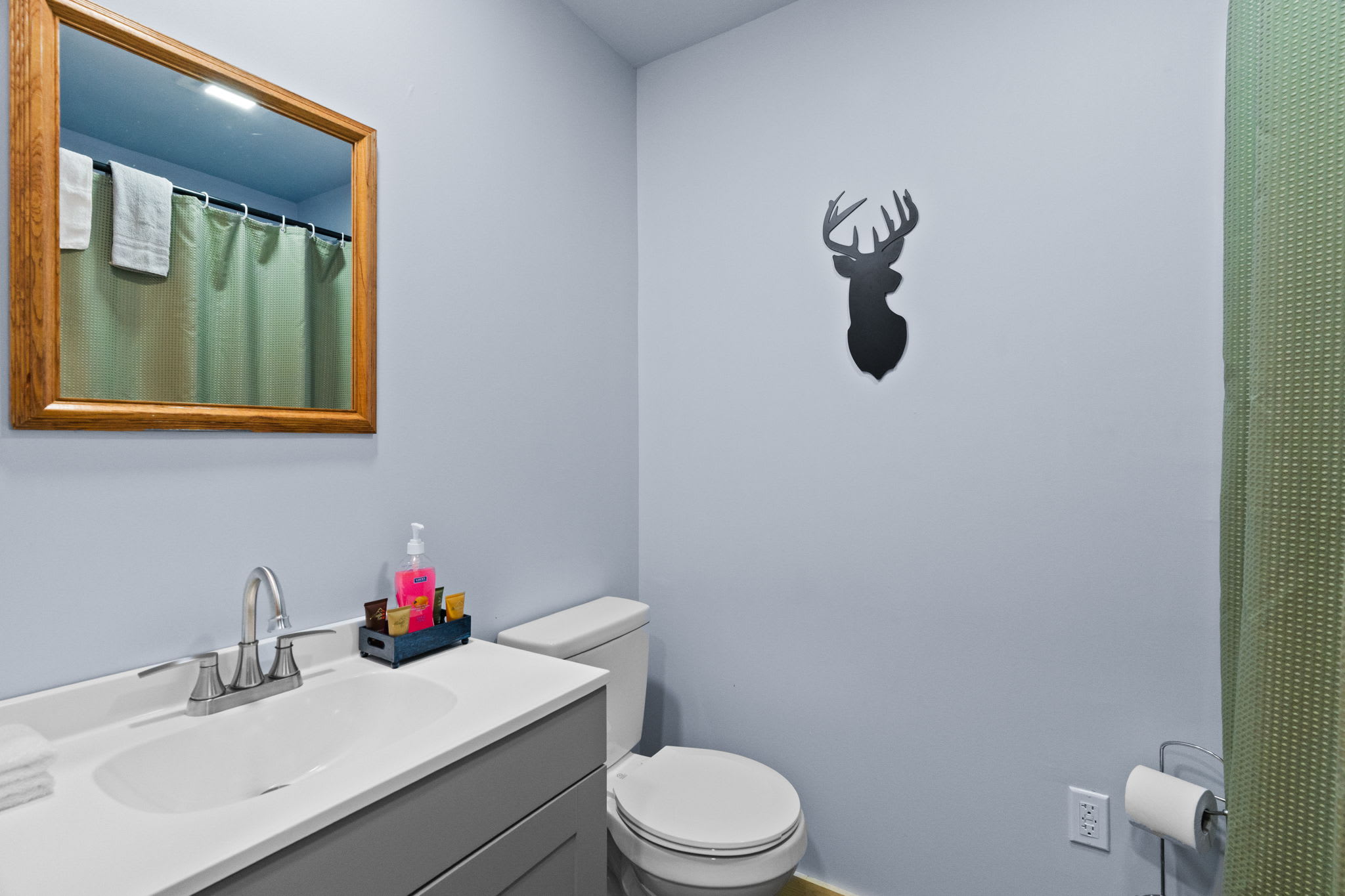 Clean and tidy bathroom with vanity and nature-themed wall art