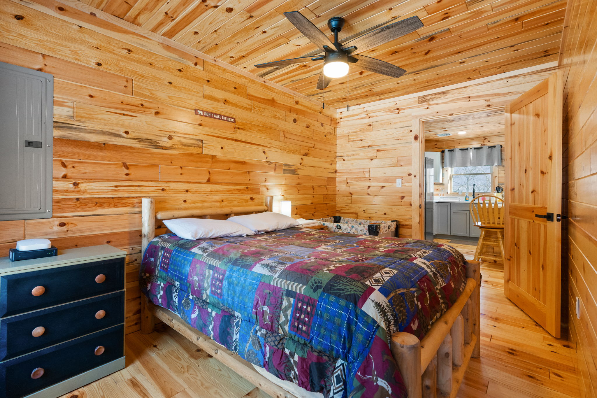 Bedroom with log bed frame and dresser opens to the main-level hallway