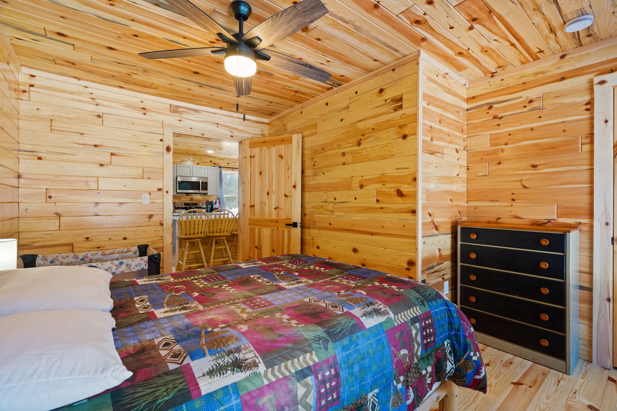 A ceiling fan and dresser storage keep this cabin bedroom comfortable and convenient