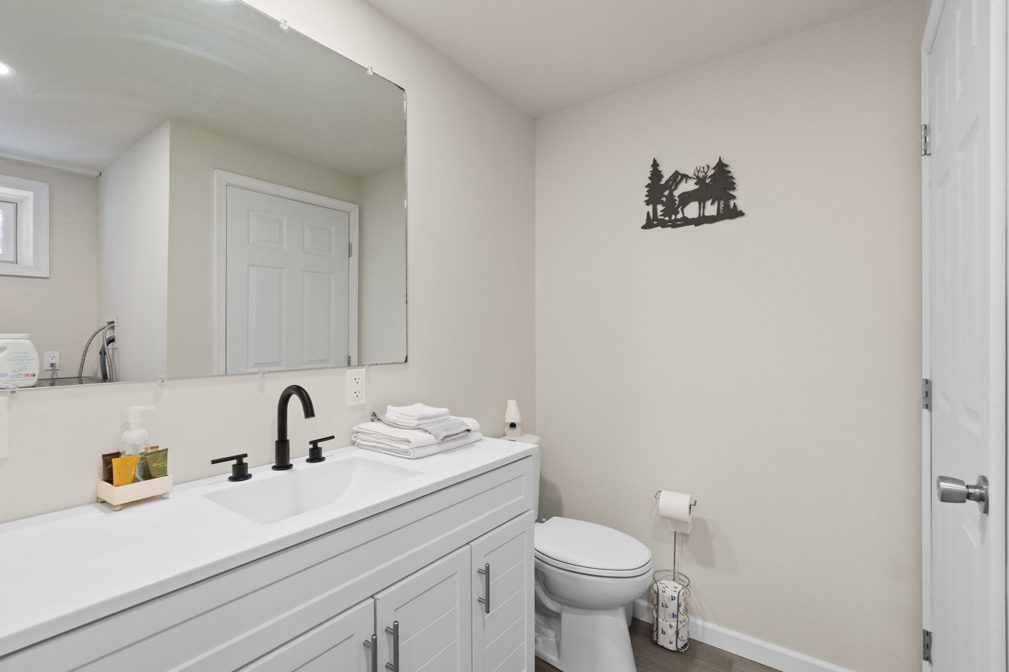 Spacious double vanity bathroom with stacked towels and woodland decor