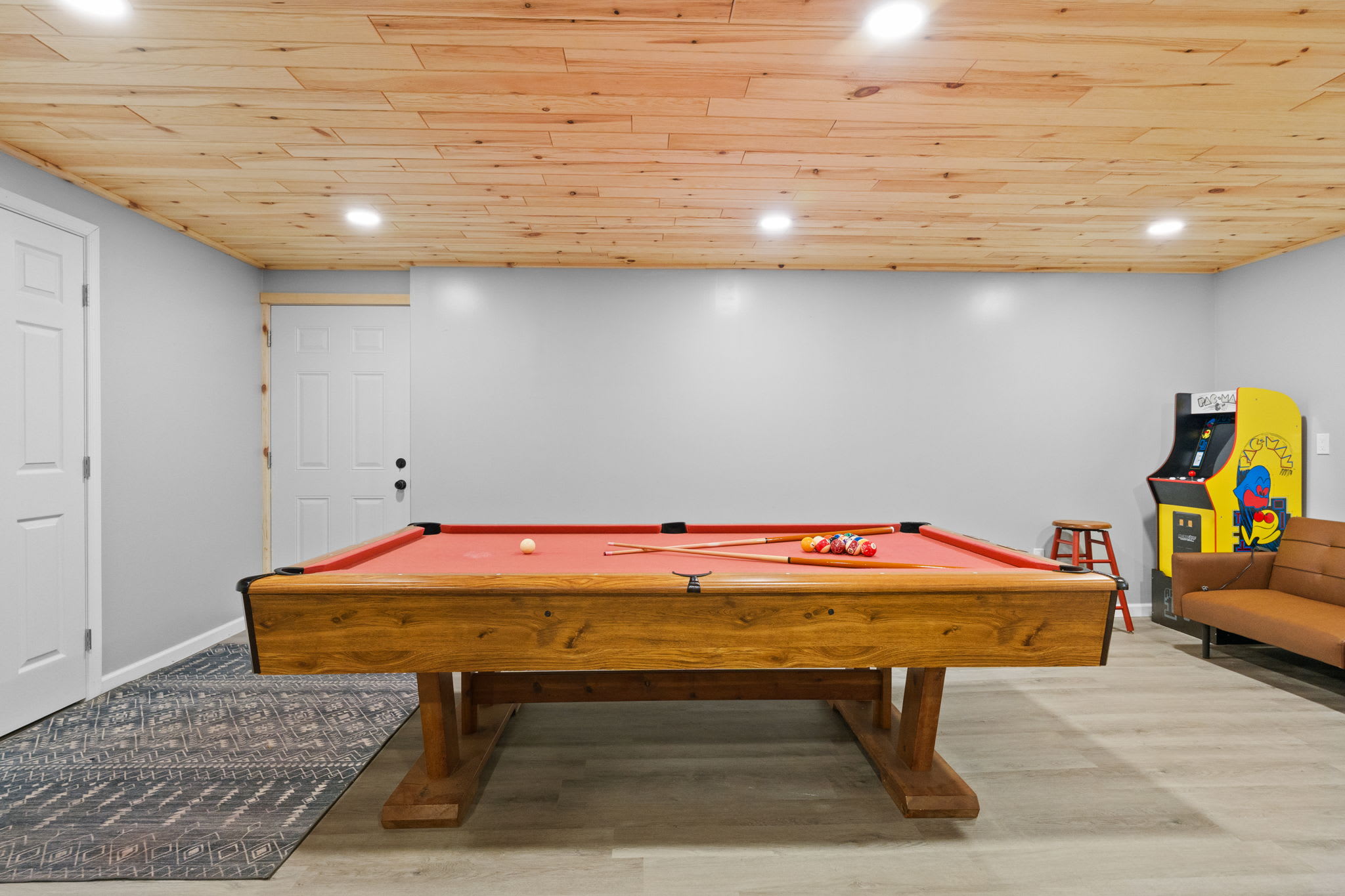 A wide view of the game room with pool table, arcade cabinet, and plenty of space to play