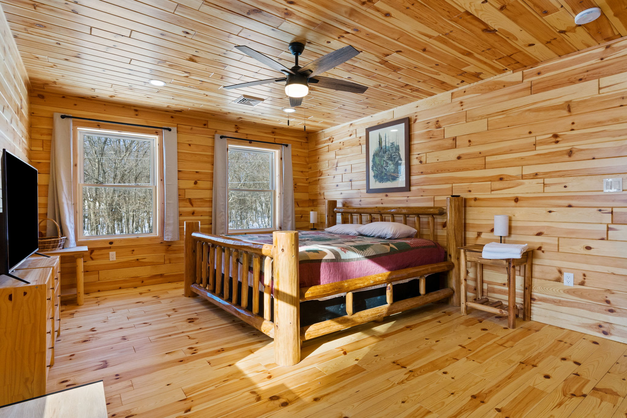 Tuck in for the night in this charming cabin bedroom with forest views