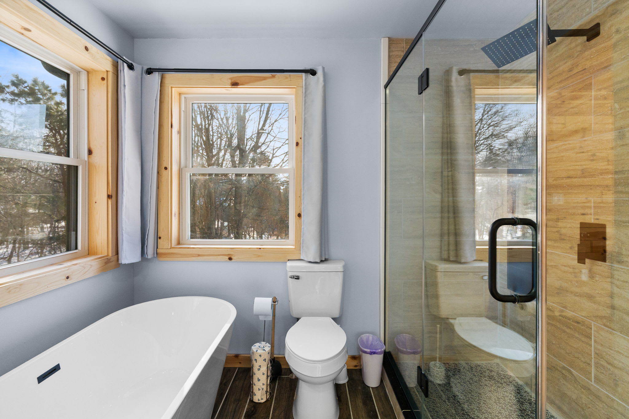 The spa-like bathroom features a deep soaking tub framed by cabin windows
