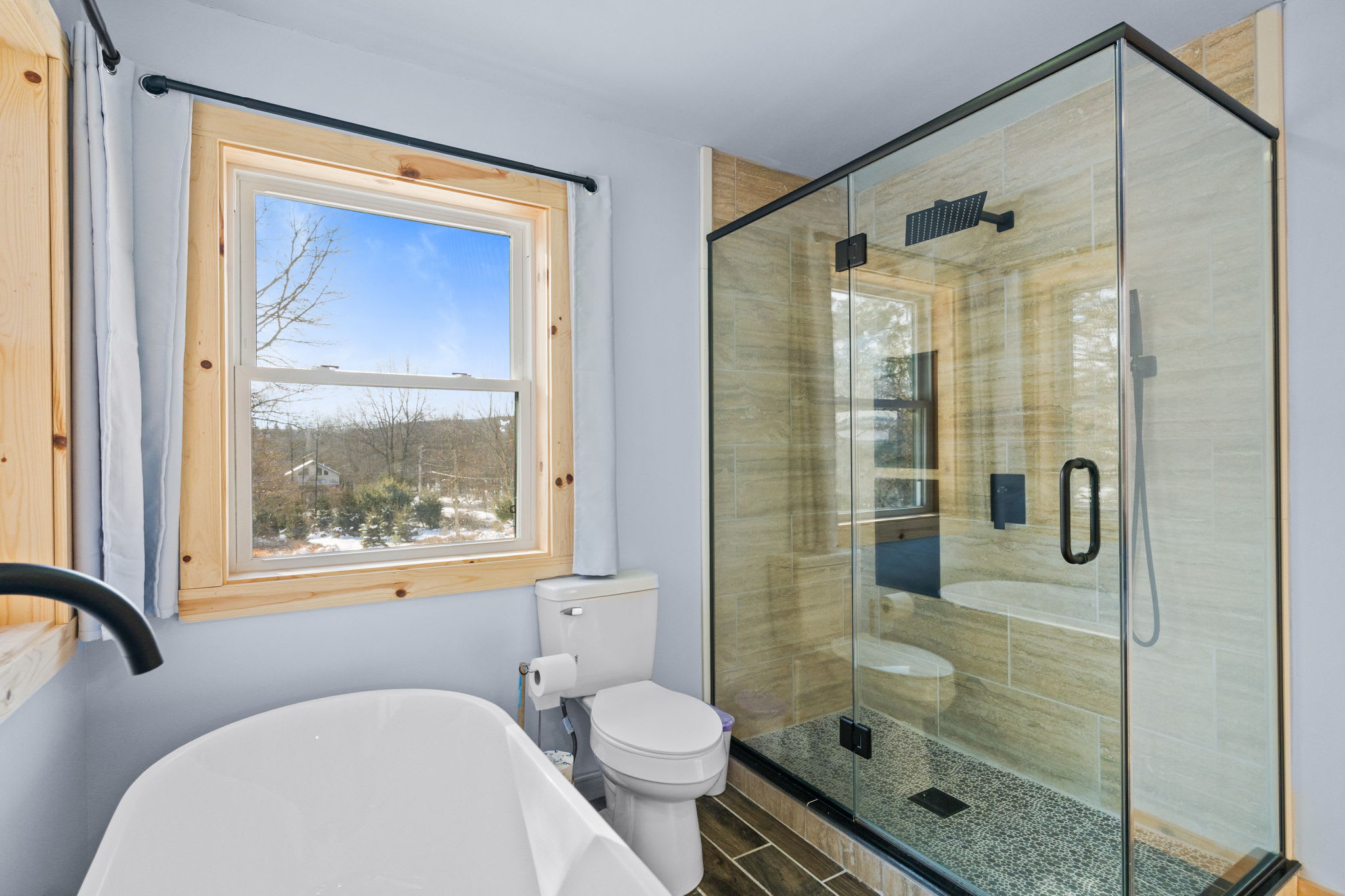 Fresh and bright bathroom with a shower-tub combo and snowy woodland views