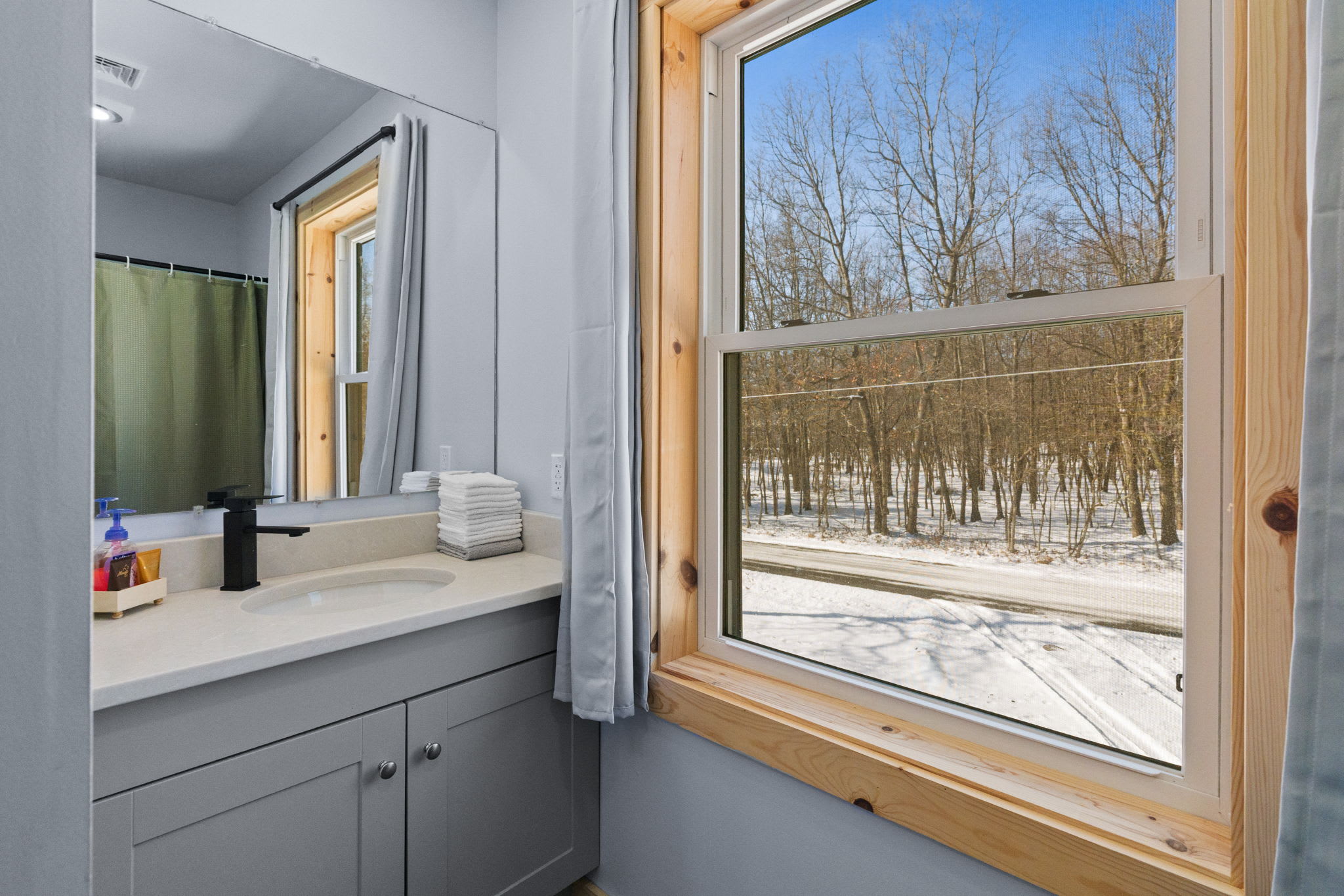 A neat vanity and window with treetop views brighten up this cabin bathroom