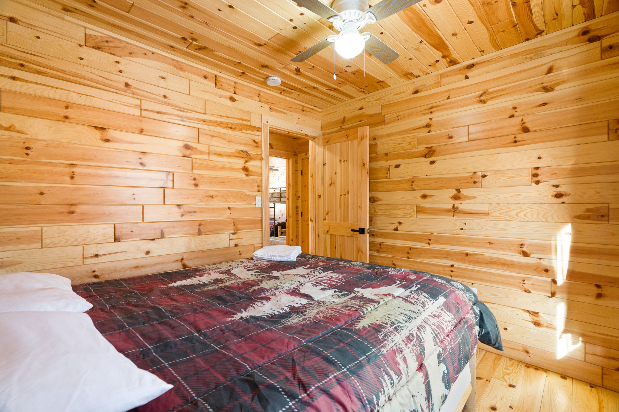 Rest easy in this warm cabin bedroom with log walls and soft bedding