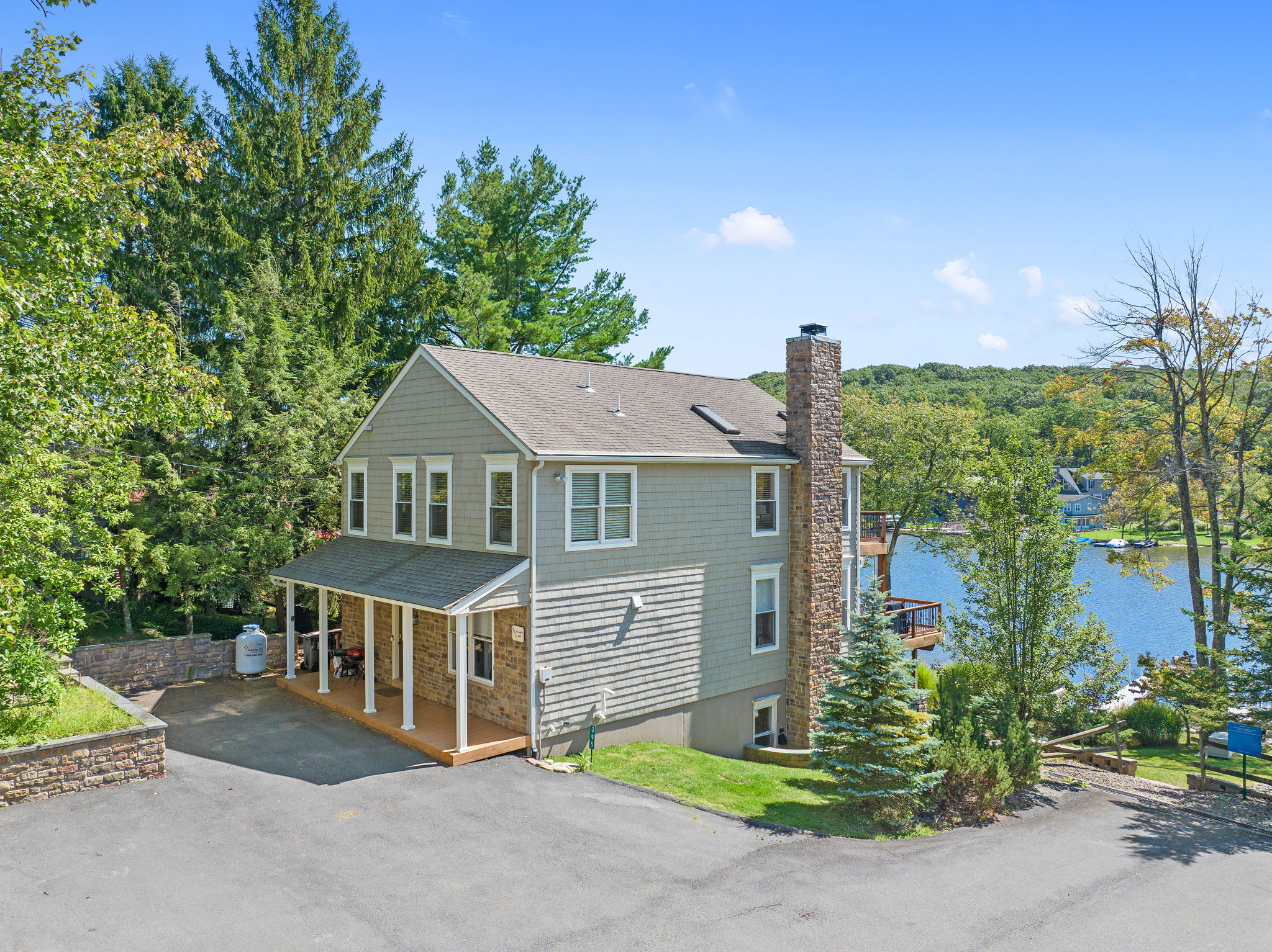 Aerial of the lake house with the shimmering water just beyond the tree line