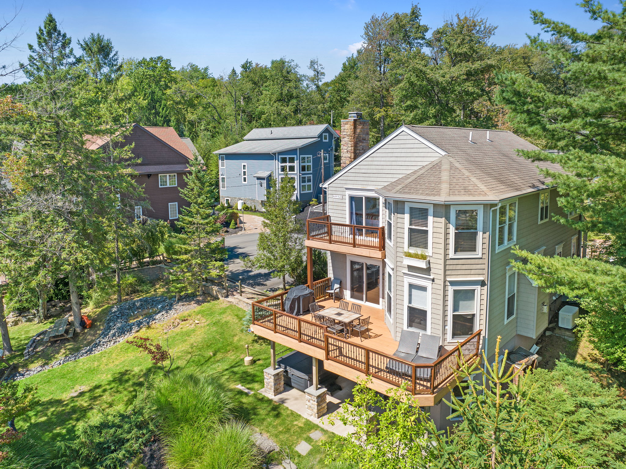 Side view of the multi-level lake house with wraparound decks and lush greenery