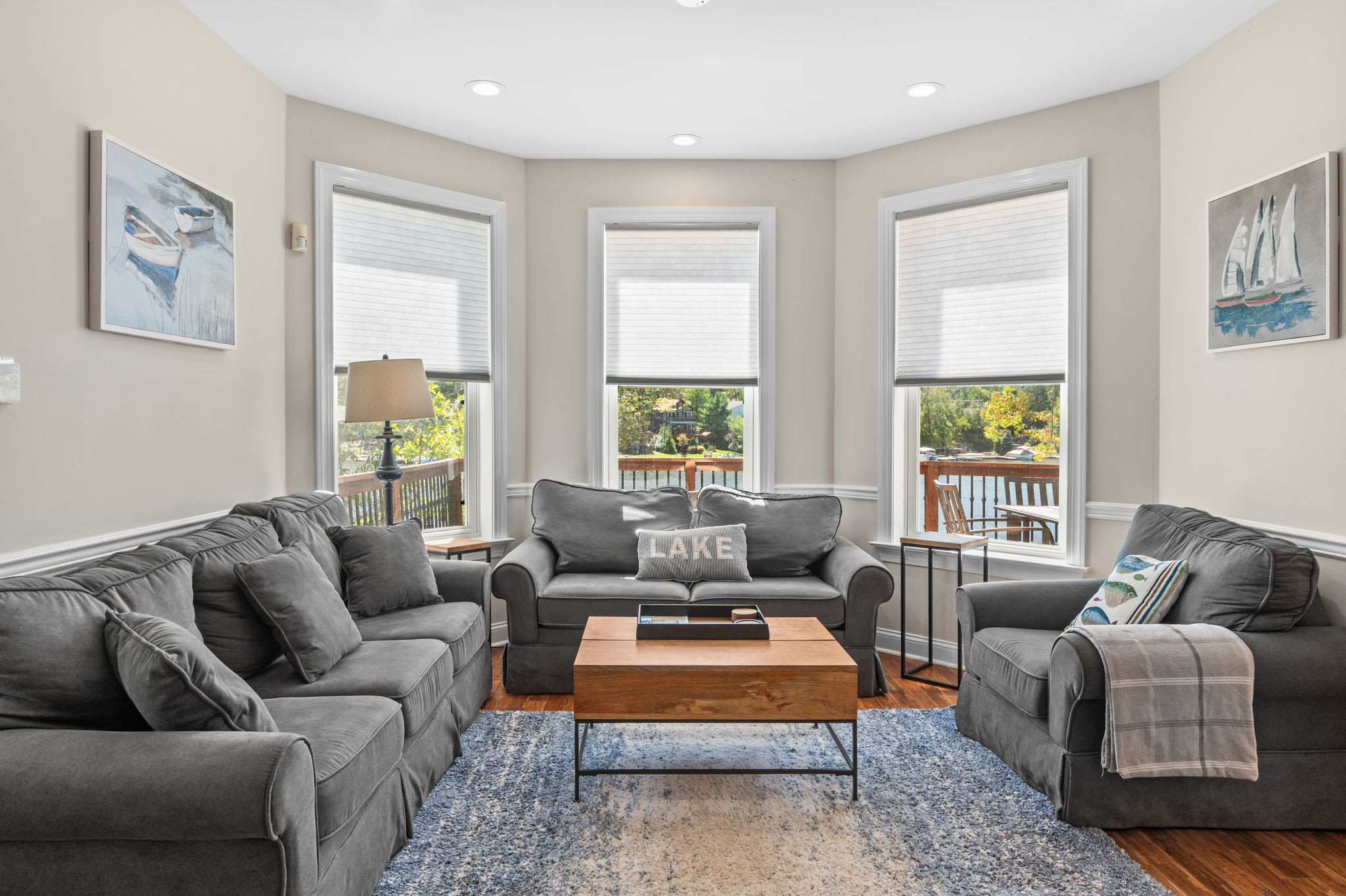 Natural light fills the living room through oversized bay windows with lake views
