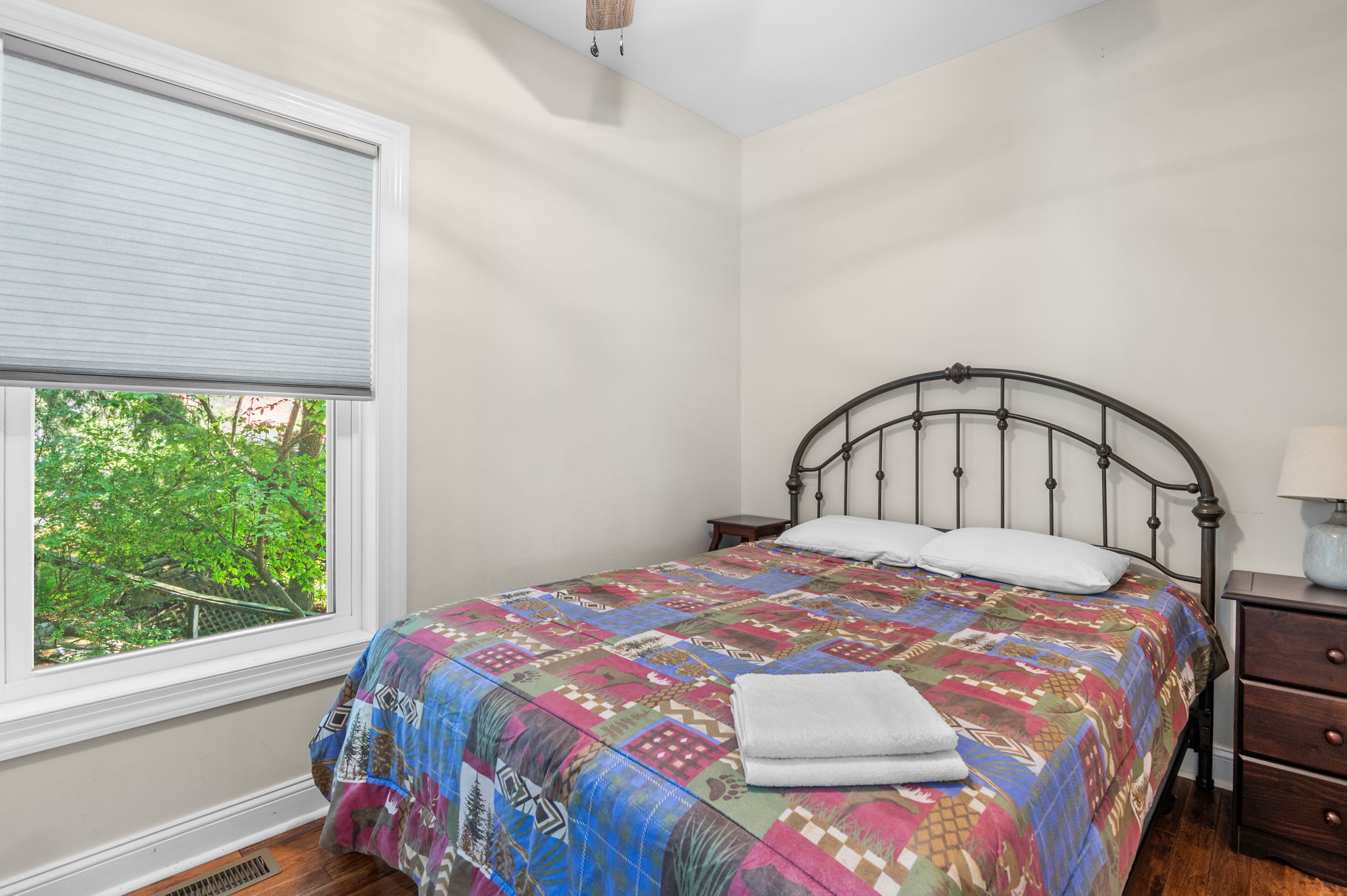 Rest easy in this cozy bedroom with a colorful quilt and garden views