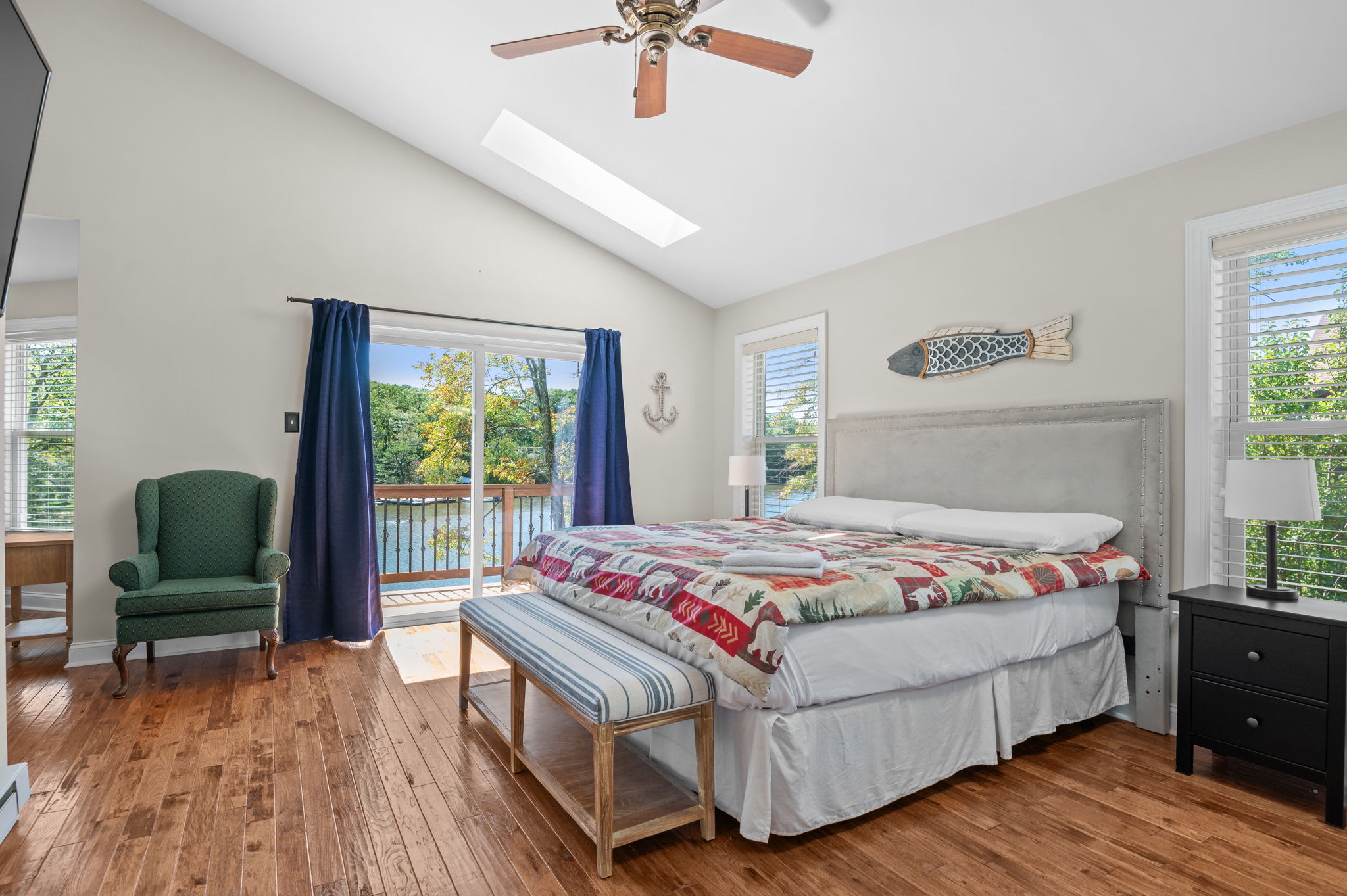 Peaceful bedroom with a queen bed, ceiling fan, and blue curtained windows