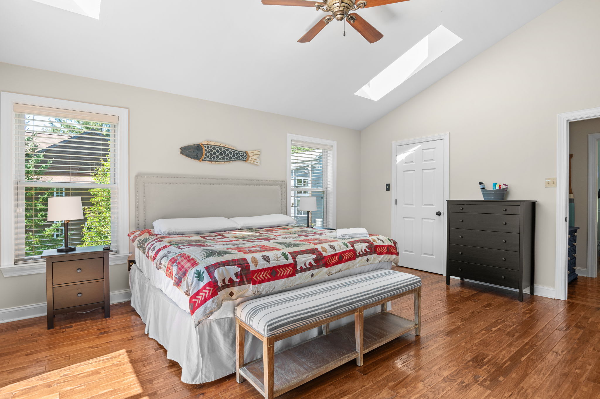 Spacious bedroom with a skylight, vaulted ceiling, and cozy lodge-style quilt