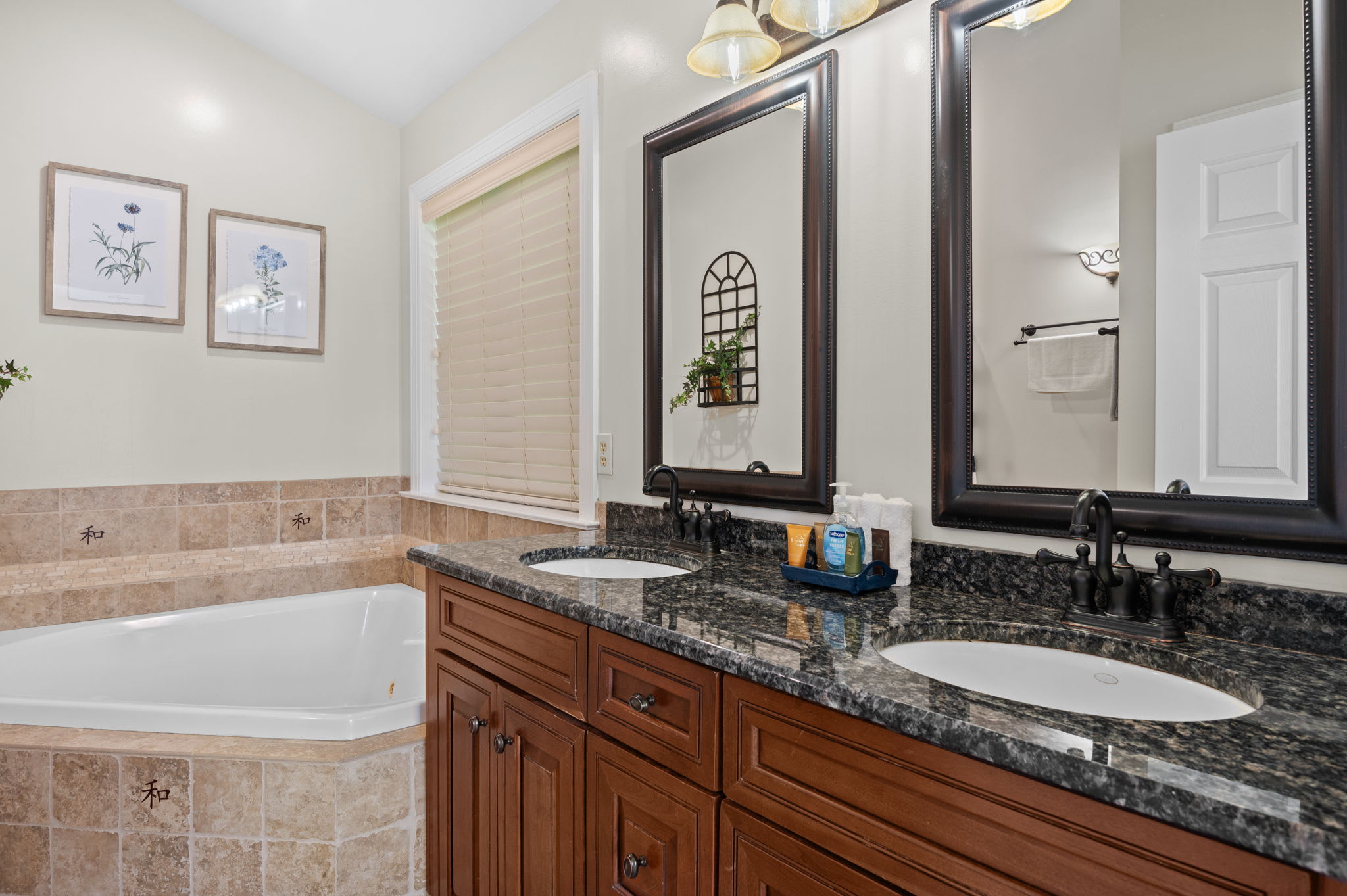Master bathroom with double vanity, granite counters, and a soaking tub