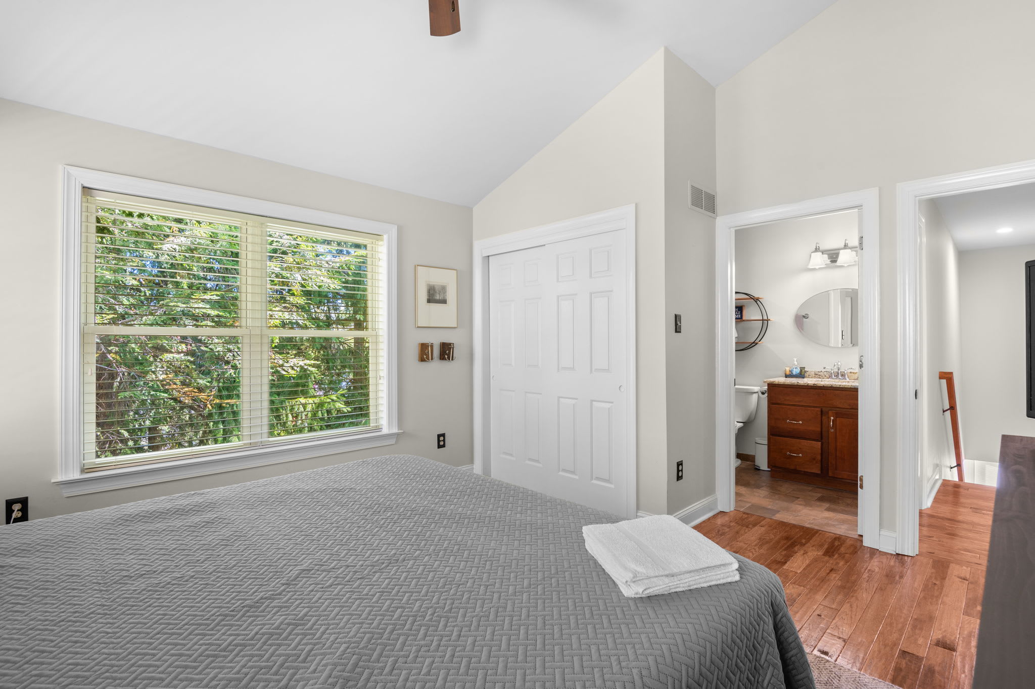 Bright and airy bedroom with hardwood floors and a view of the trees
