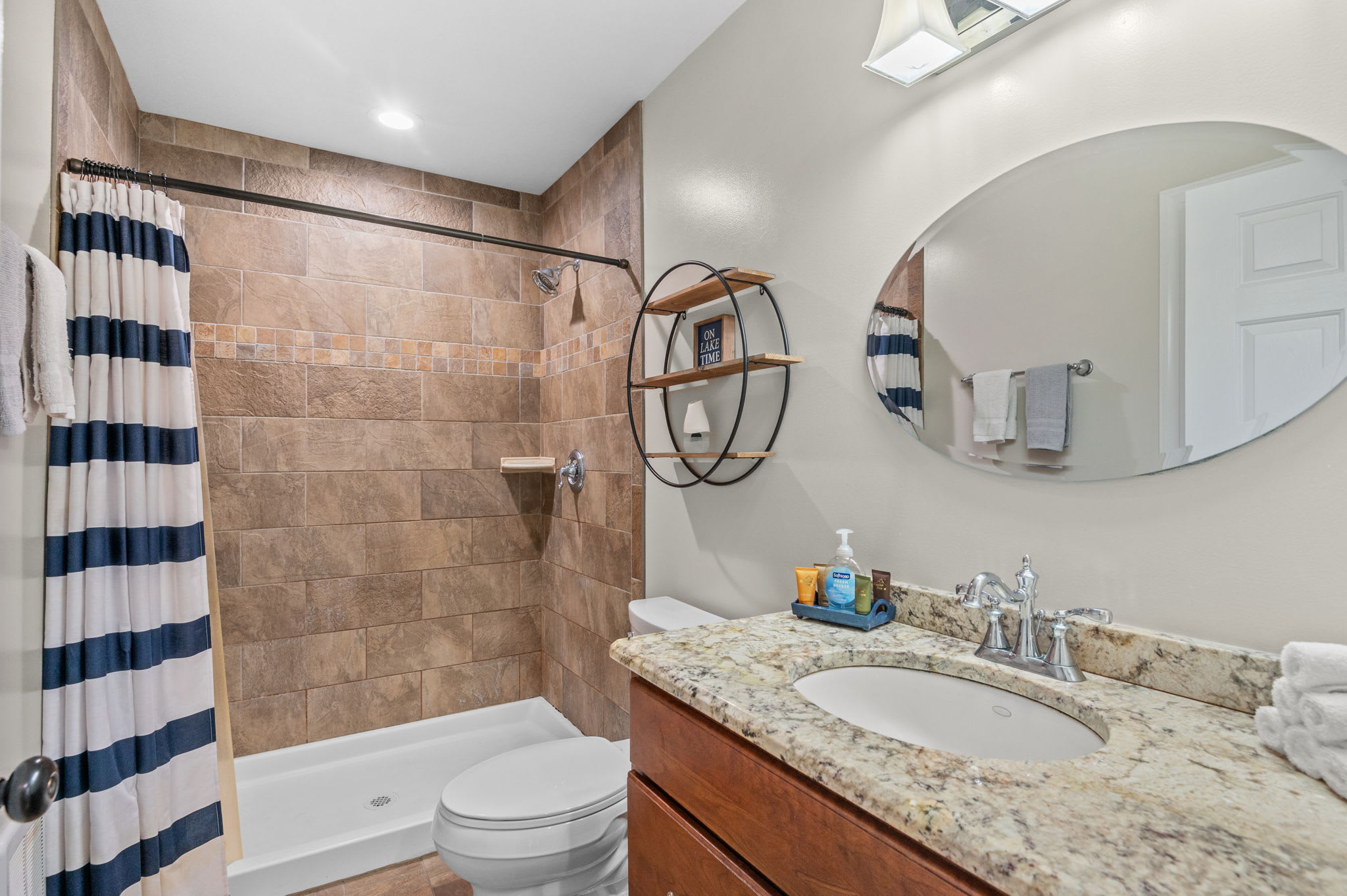 Clean and cheerful bathroom with a striped curtain, vanity, and tiled floor