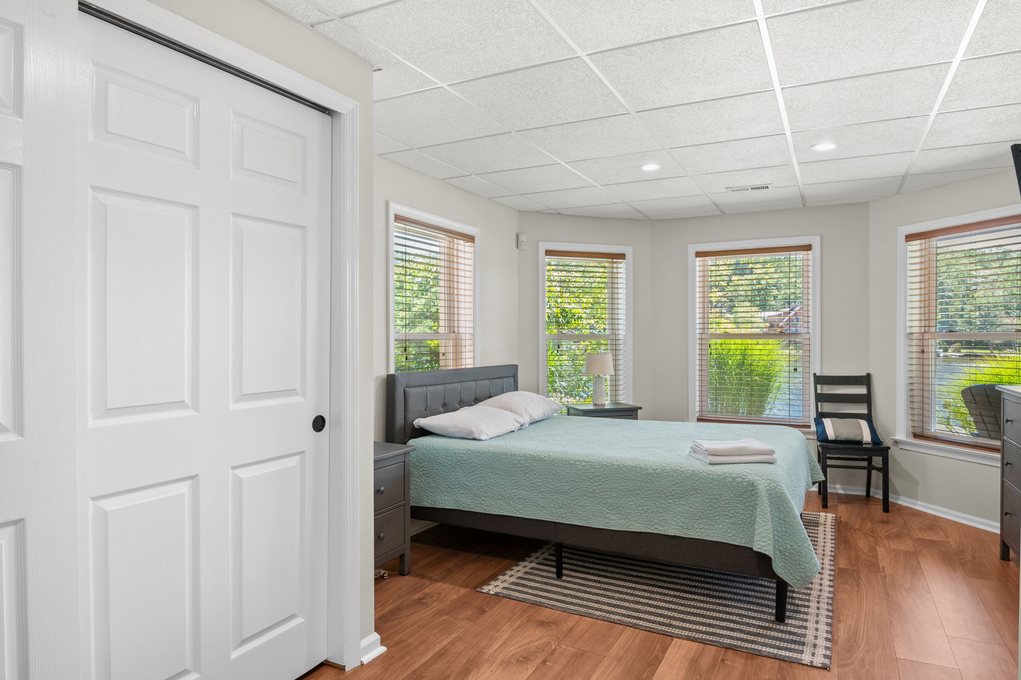 Lower-level bedroom with natural light and serene green bedding