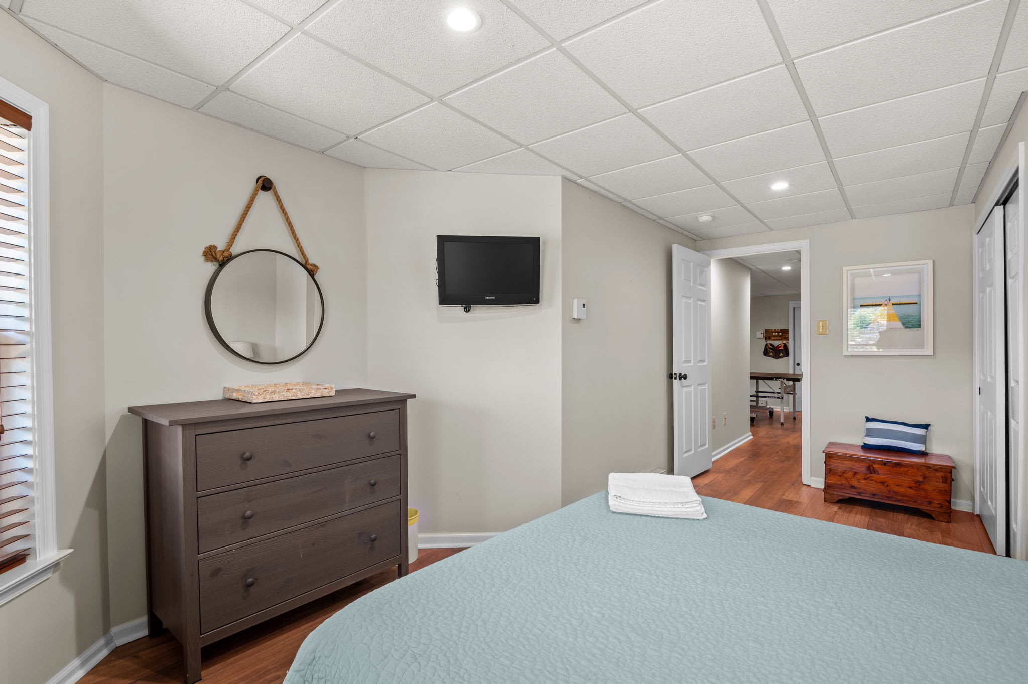 Quiet lower-level bedroom with a dresser, TV, and warm hardwood floors