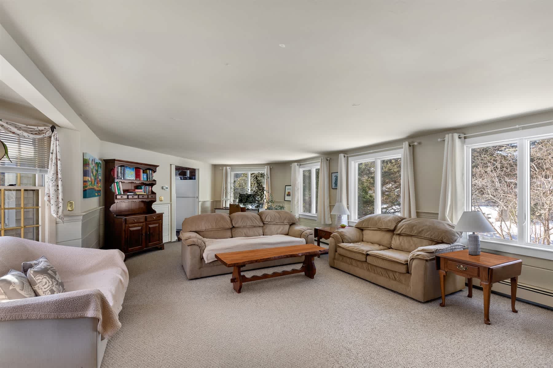 Spacious living area with plentiful seating and sunny windows, a welcoming gathering spot for your stay in Eastham on Cape Cod.