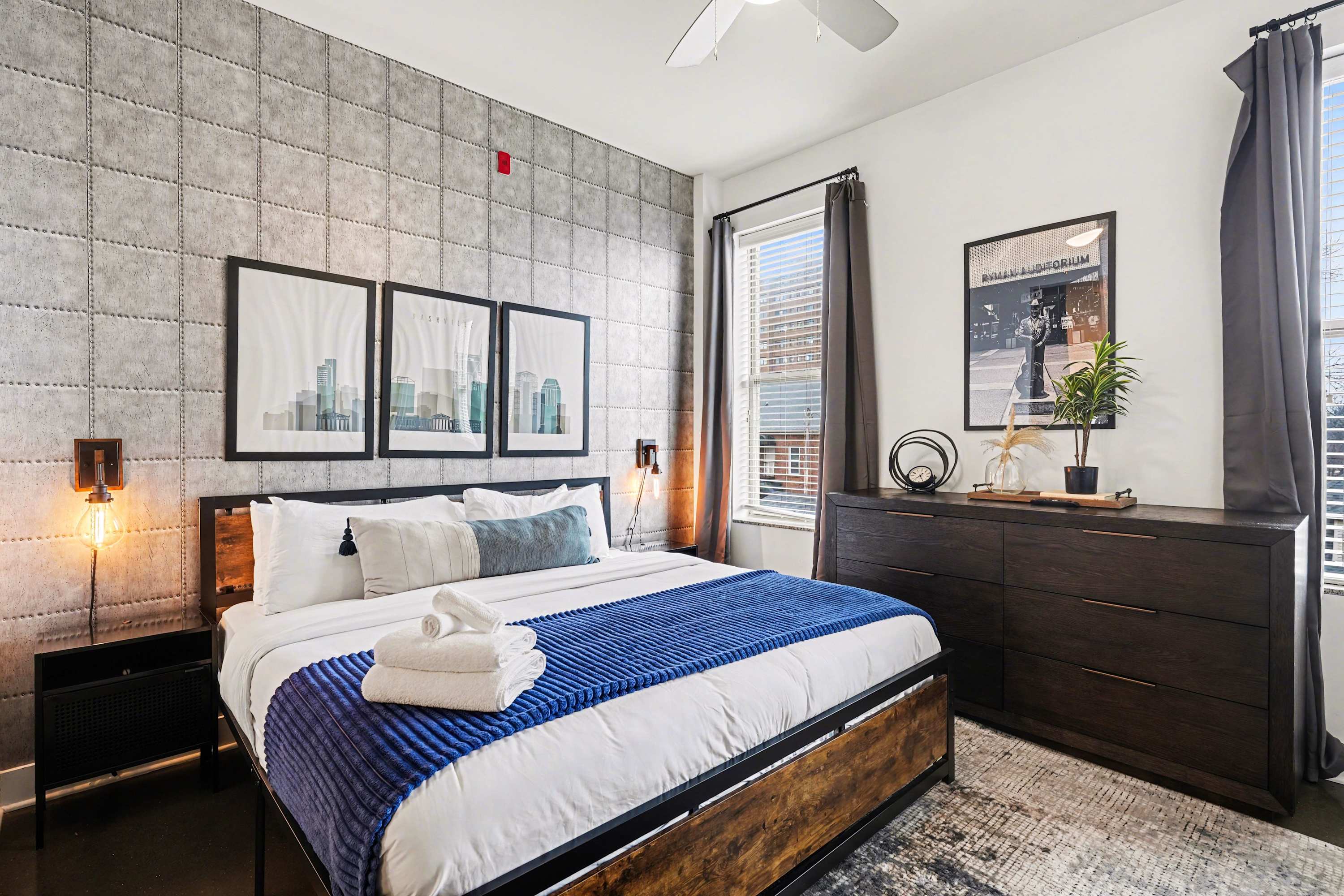 Sleep soundly in this king bedroom featuring industrial-chic decor, dual windows, and a large smart TV.