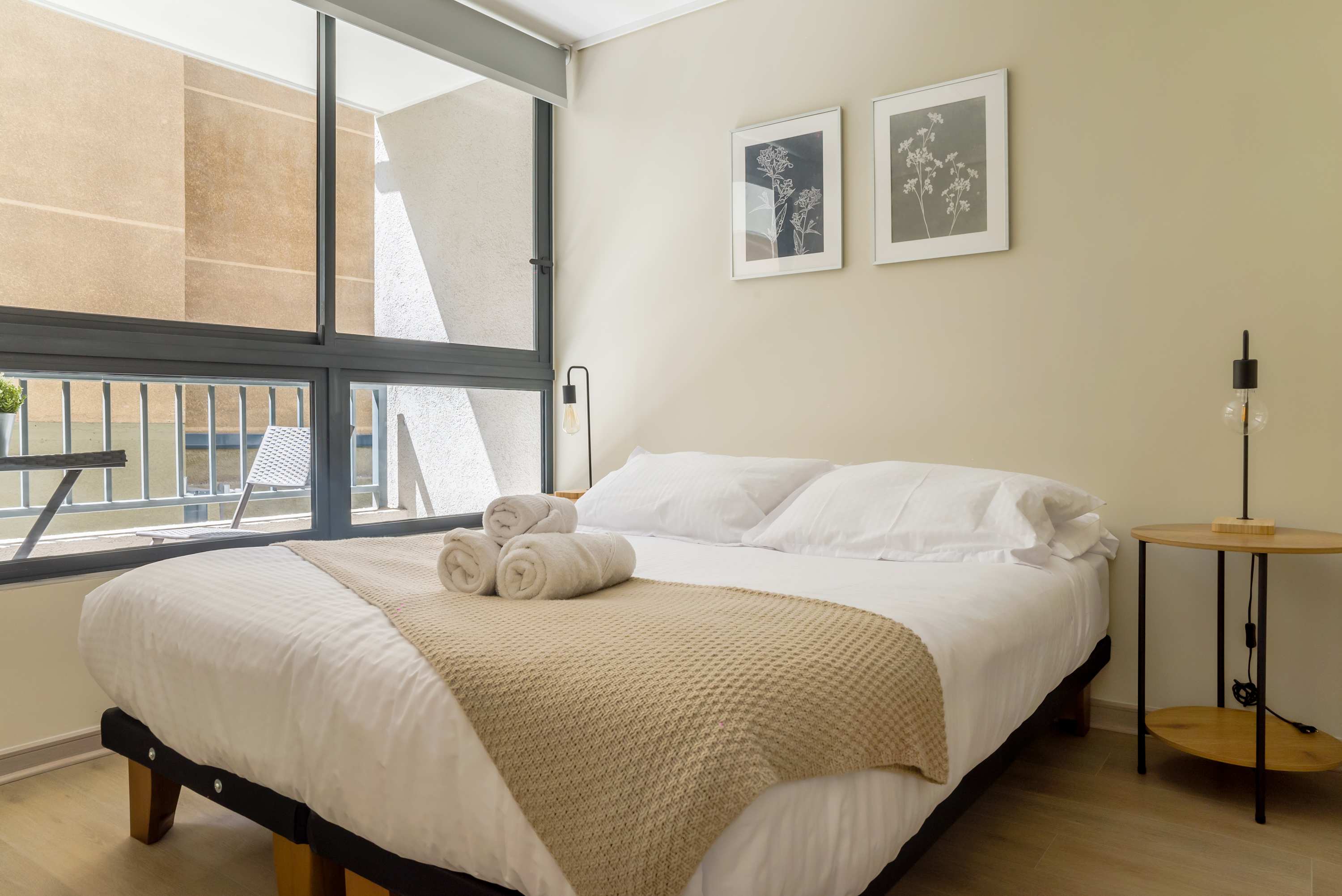 Relax in this bright and cozy bedroom with large windows and stylish decor, perfect for unwinding after a day of exploring.