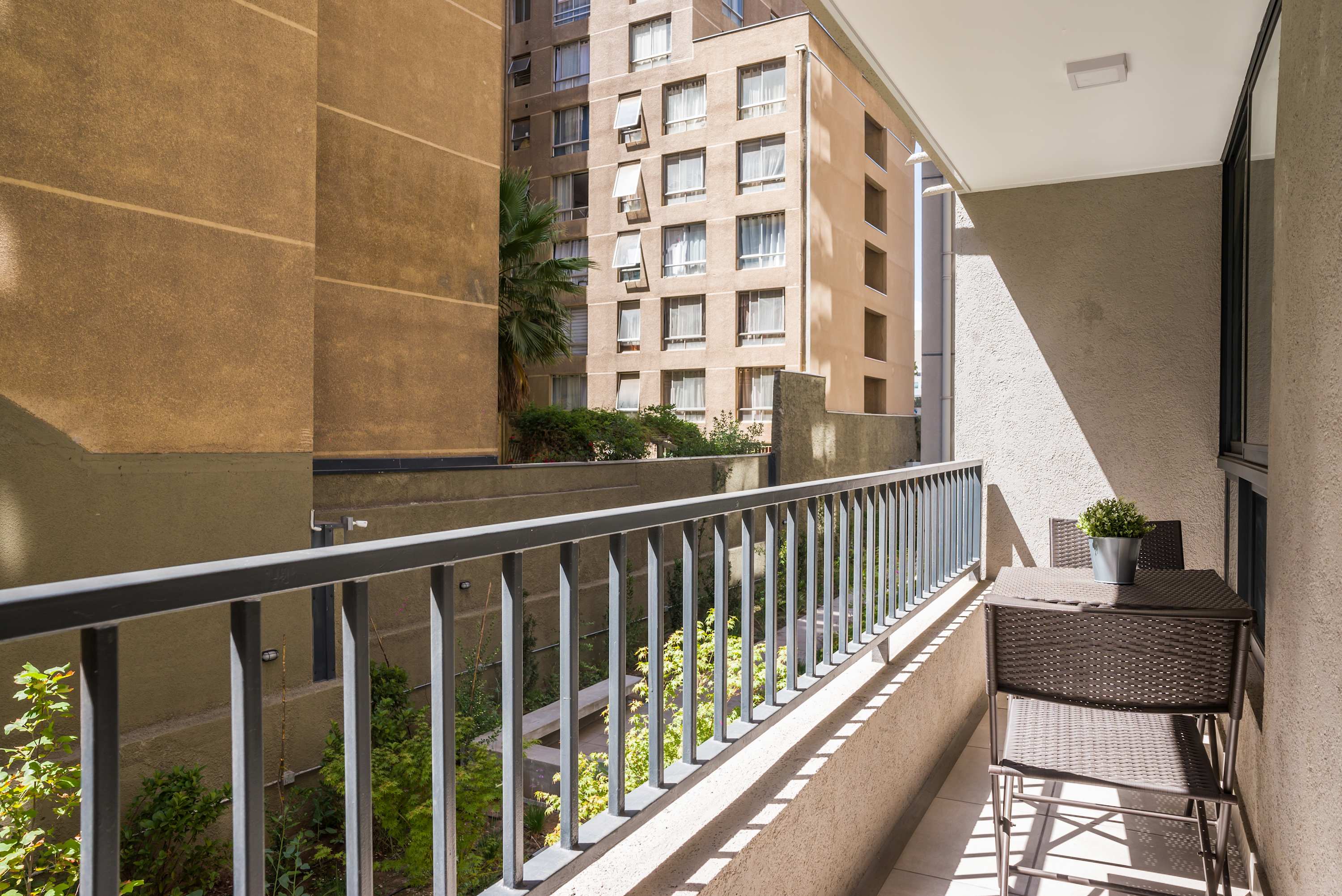 Enjoy your morning coffee on this sunny balcony with a view of the cityscape and lush greenery.