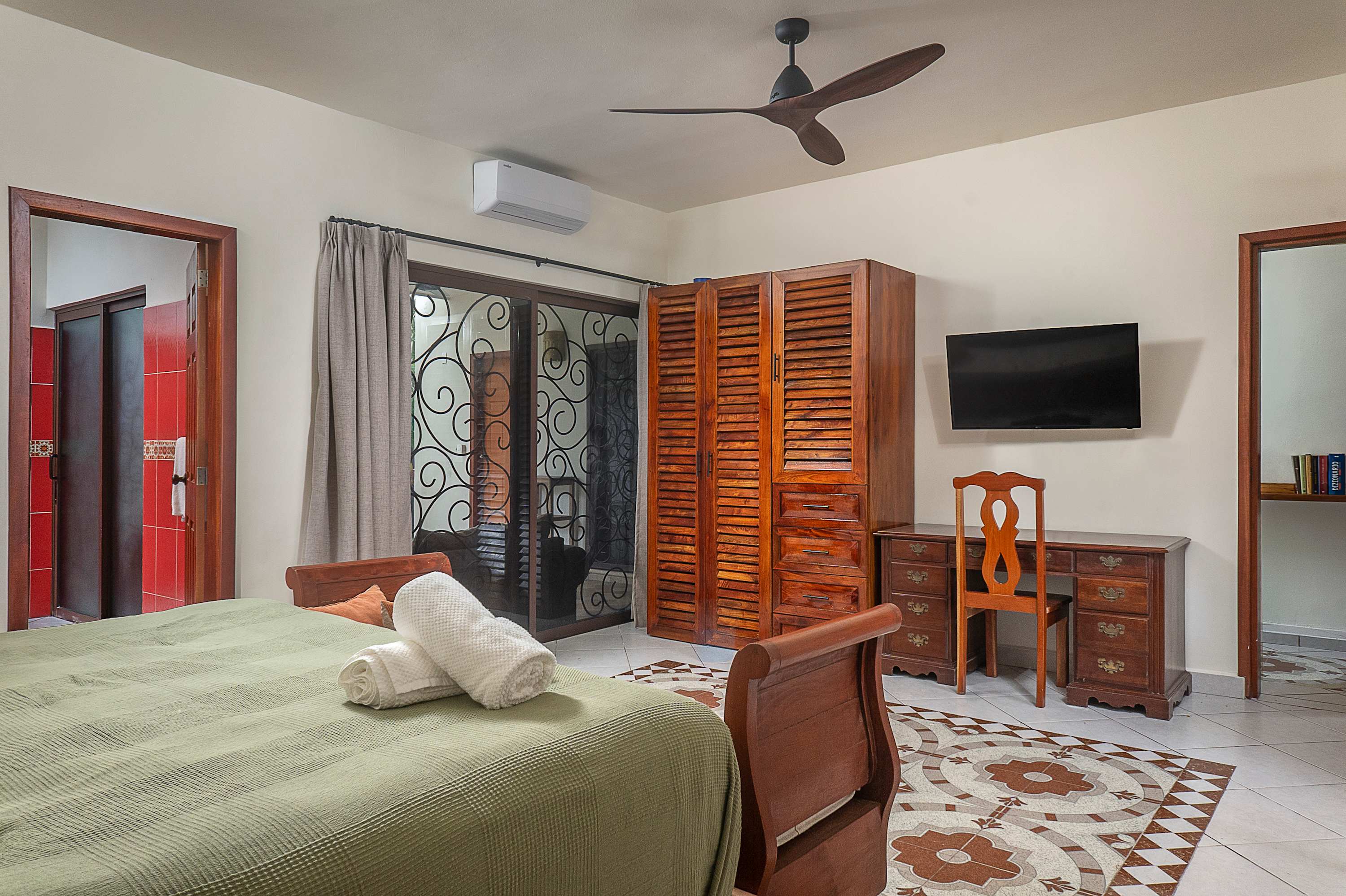 Master bedroom with a king-size bed, featuring warm wood details and an en-suite bathroom