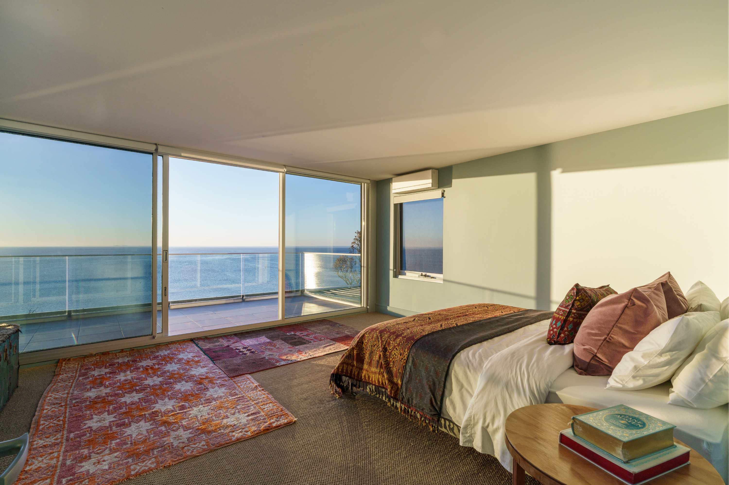 A bedroom suspended between sky and sea.
The upstairs King bedroom, with split system heating and cooling, wardrobes and balcony access