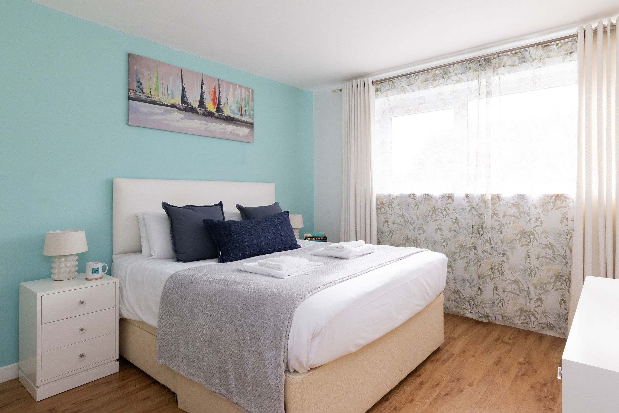 Bright double bedroom with fresh linens, soft lighting, and calming coastal tones for a restful seaside stay.