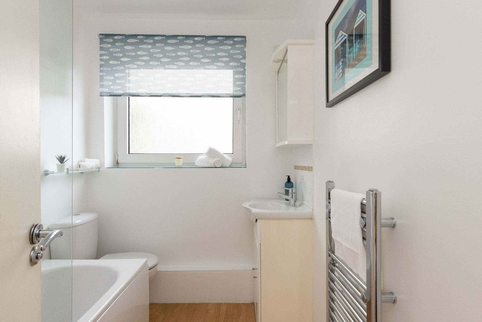 The full family bathroom has a bath with an overhead shower, WC and sink.