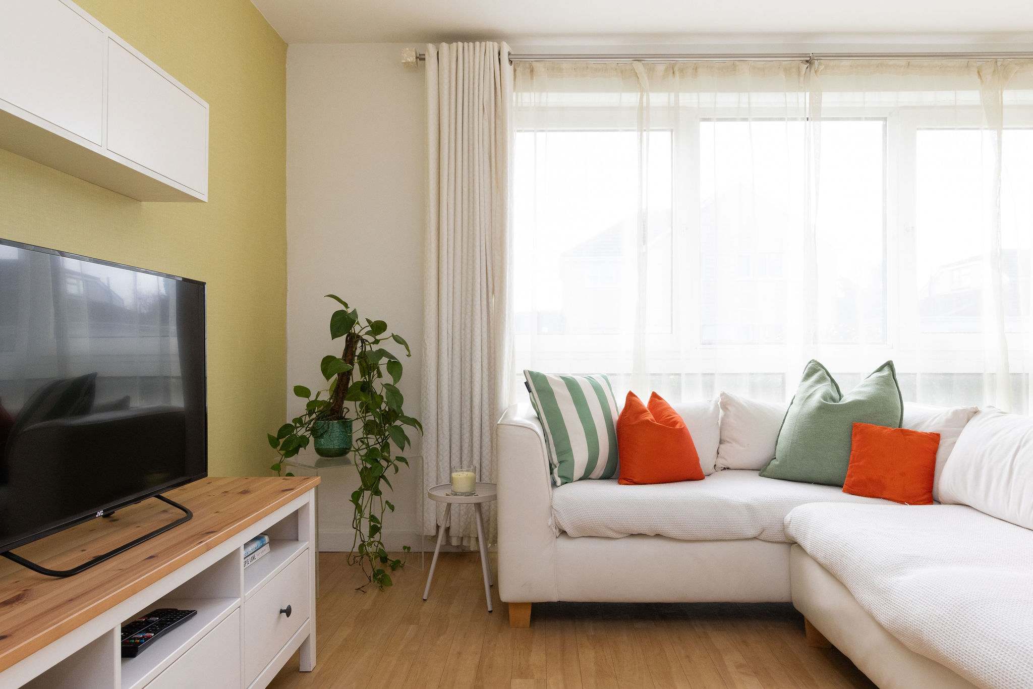 Bright open-plan living area with comfy corner sofa and Smart TV, perfect for relaxing after the beach.