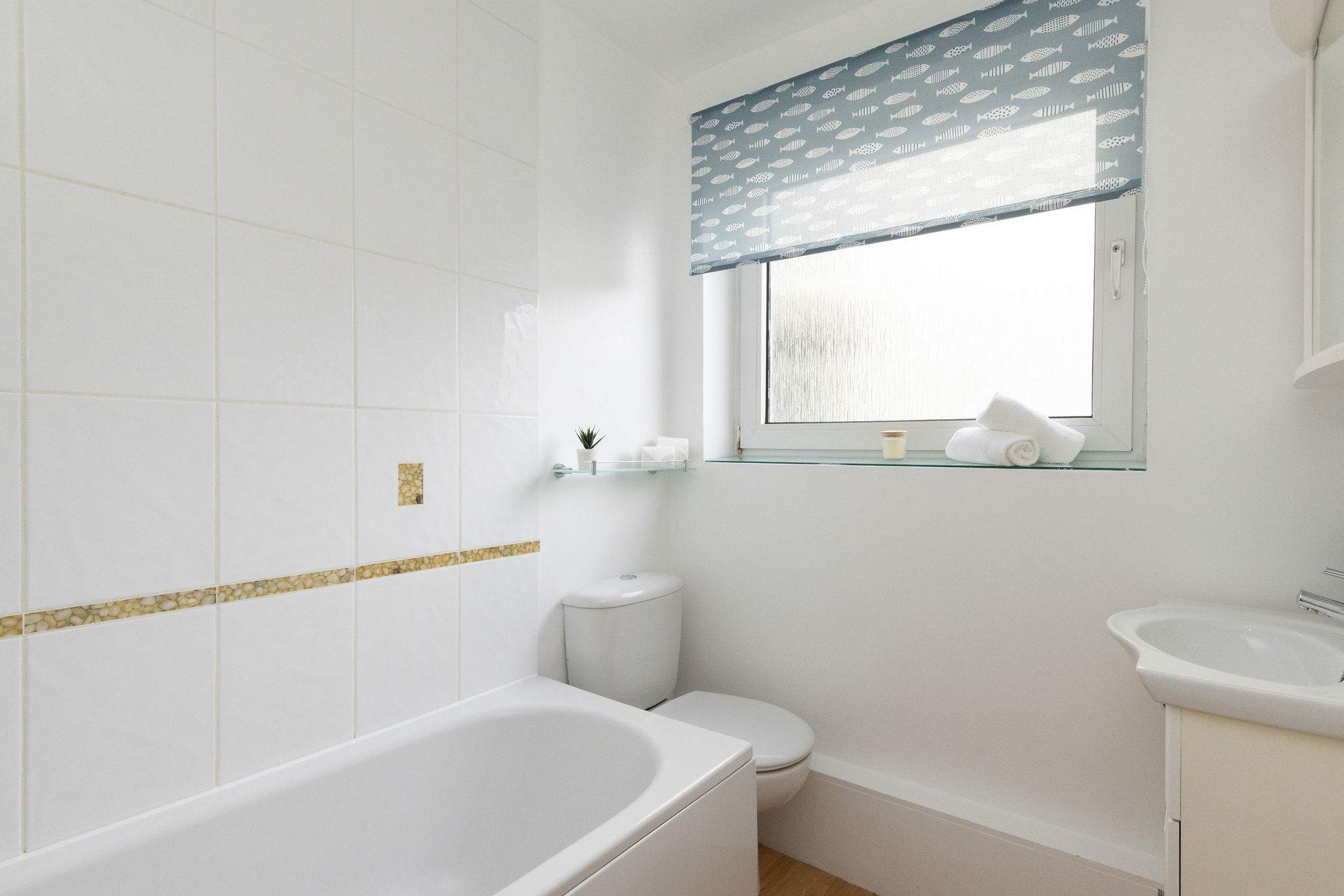 Fresh, bright bathroom with bathtub and overhead shower, perfect for relaxing after a day at the beach.