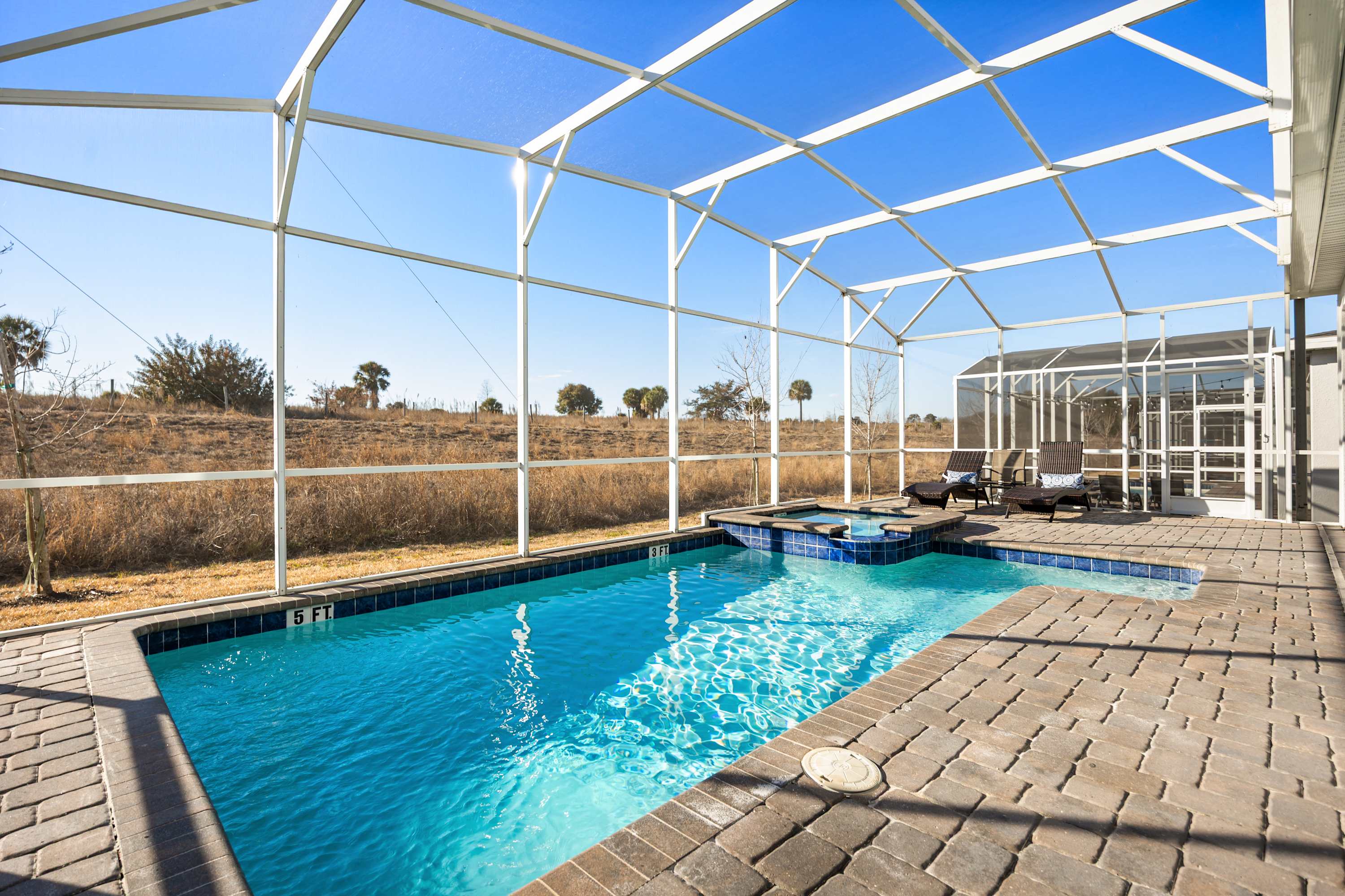 Relax in your private screened-in pool and hot tub with stunning views of the natural landscape, perfect for a serene getaway.
