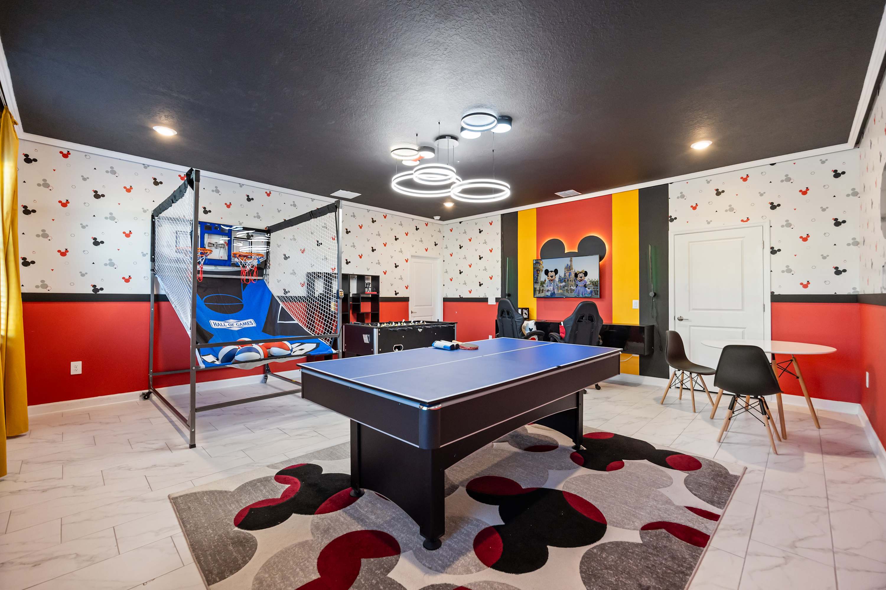 Experience endless fun in this vibrant game room with a ping pong table, arcade games, and a Mickey Mouse theme. Perfect for family entertainment!