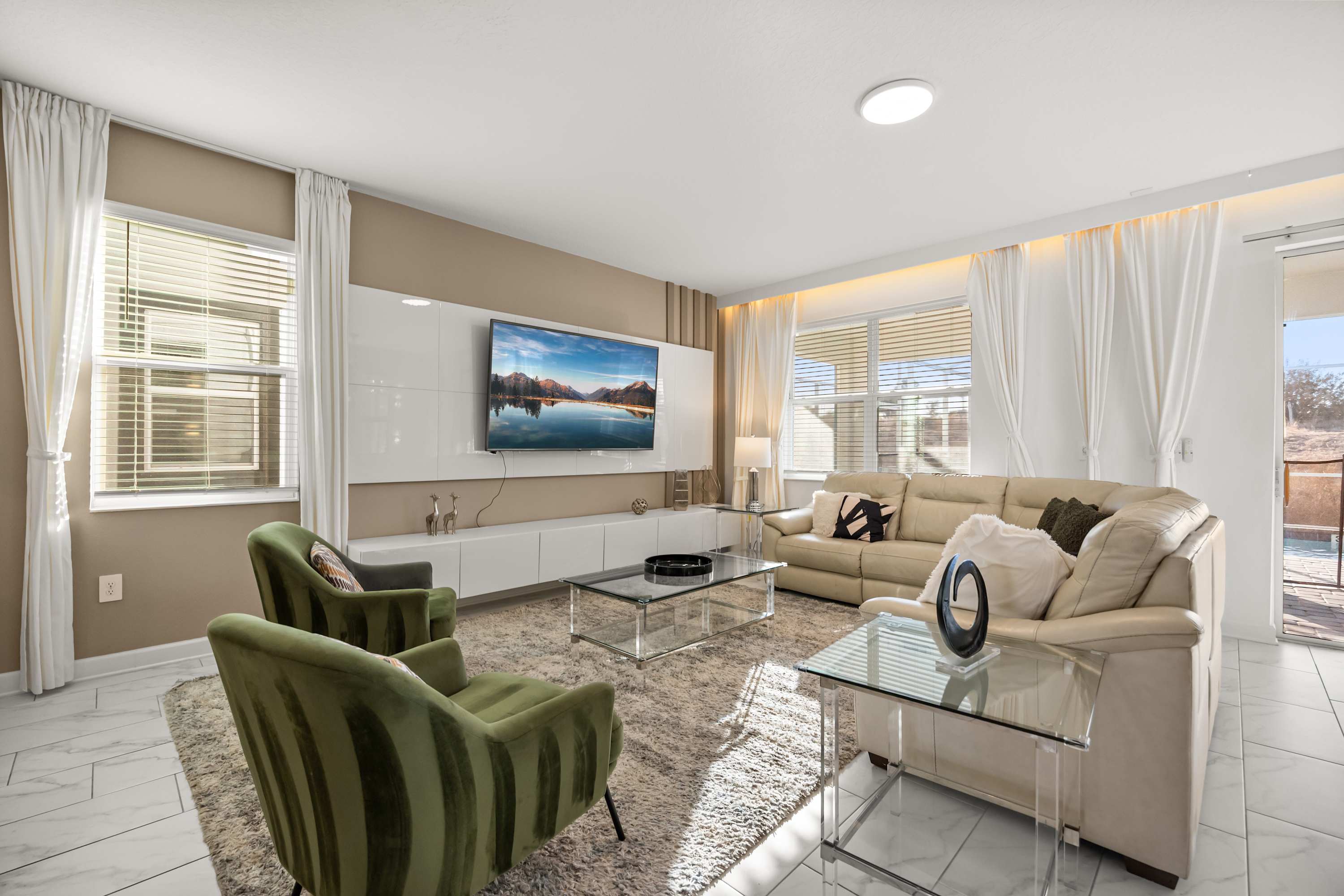 Relax in this elegant living room with plush seating, a large TV, and abundant natural light, perfect for unwinding after a day of exploring.