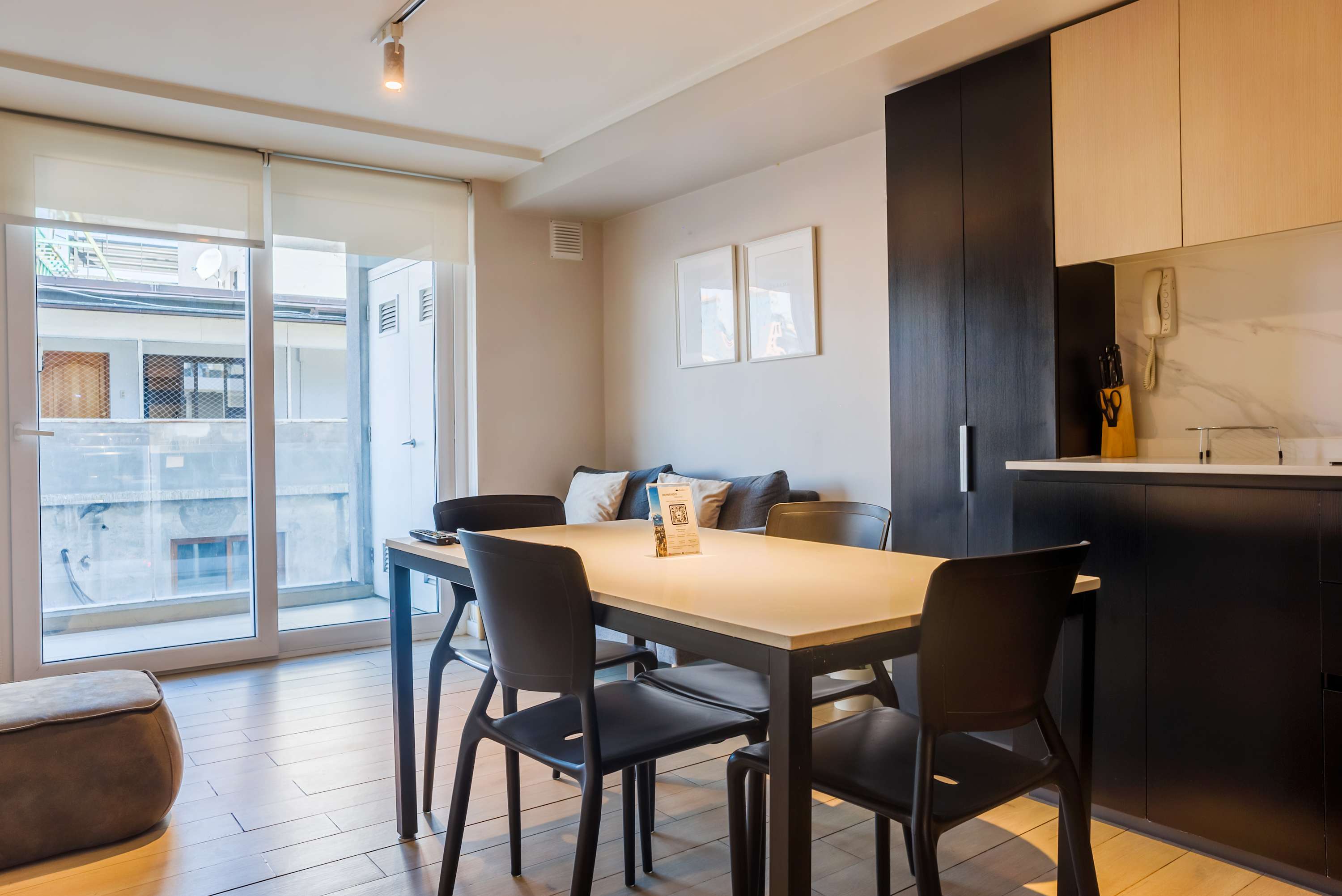 Bright dining area with modern furnishings and a cozy couch, offering a relaxing space with balcony access.