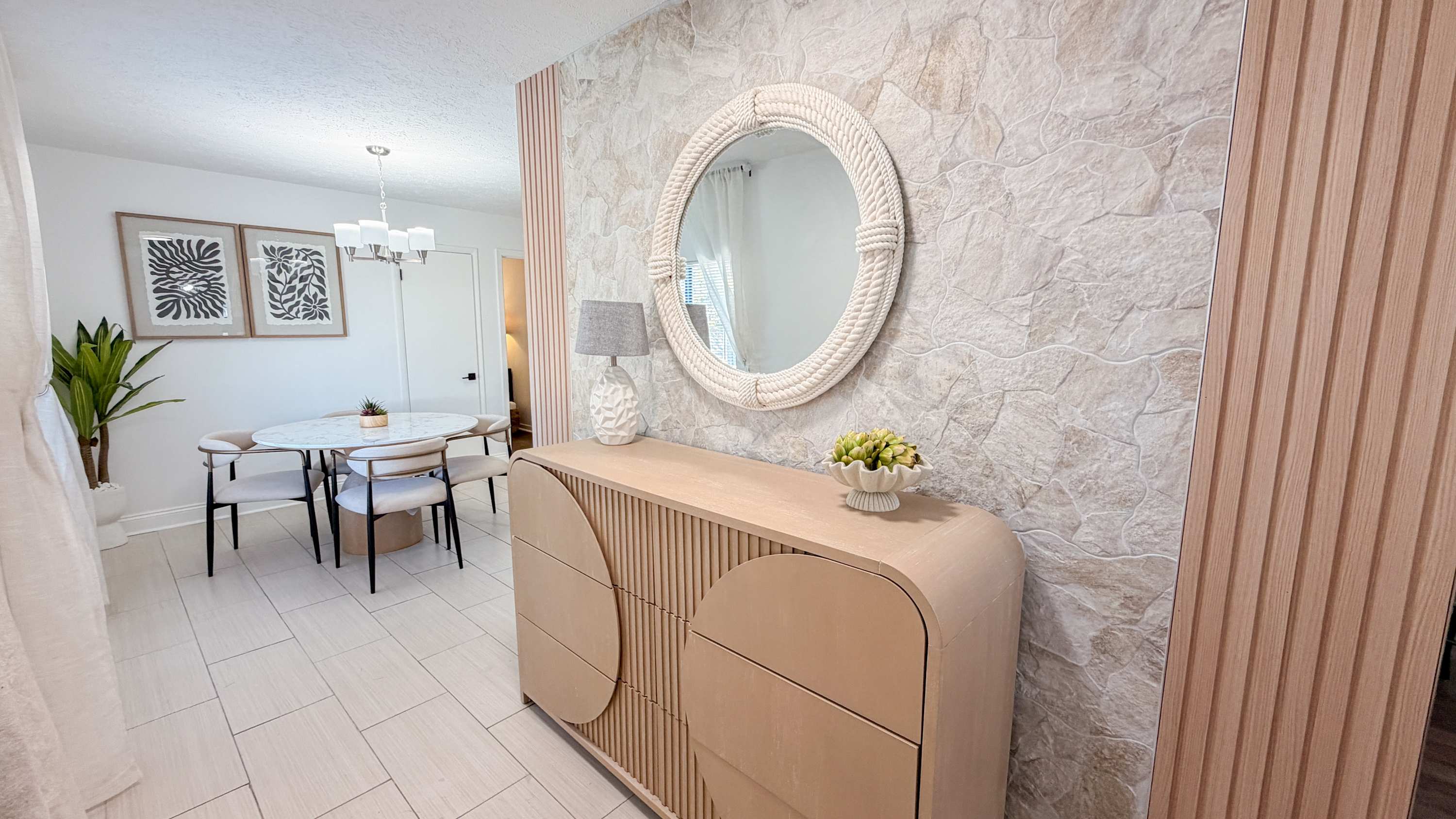 300 W 23rd Pl – Dining area with a round table, modern decor, stone wall, potted plant, and a decorative mirror.