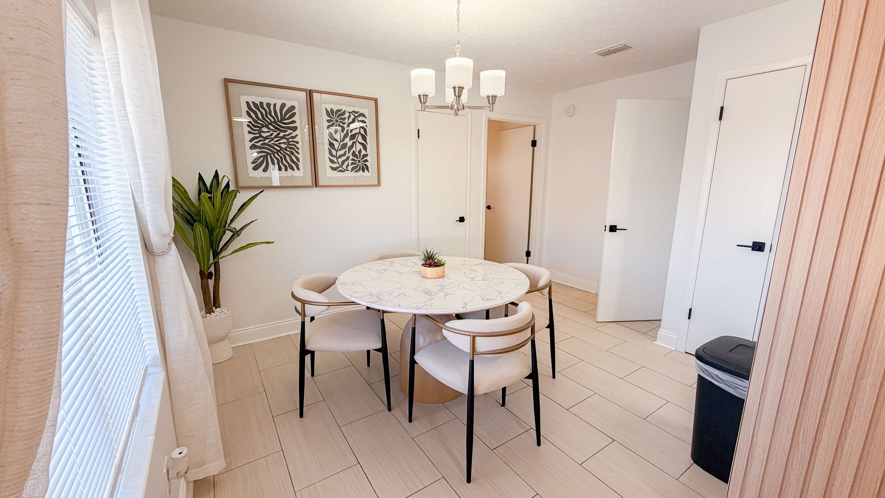 300 W 23rd Pl – Dining area with round marble table, four chairs, plants, and art on the wall.