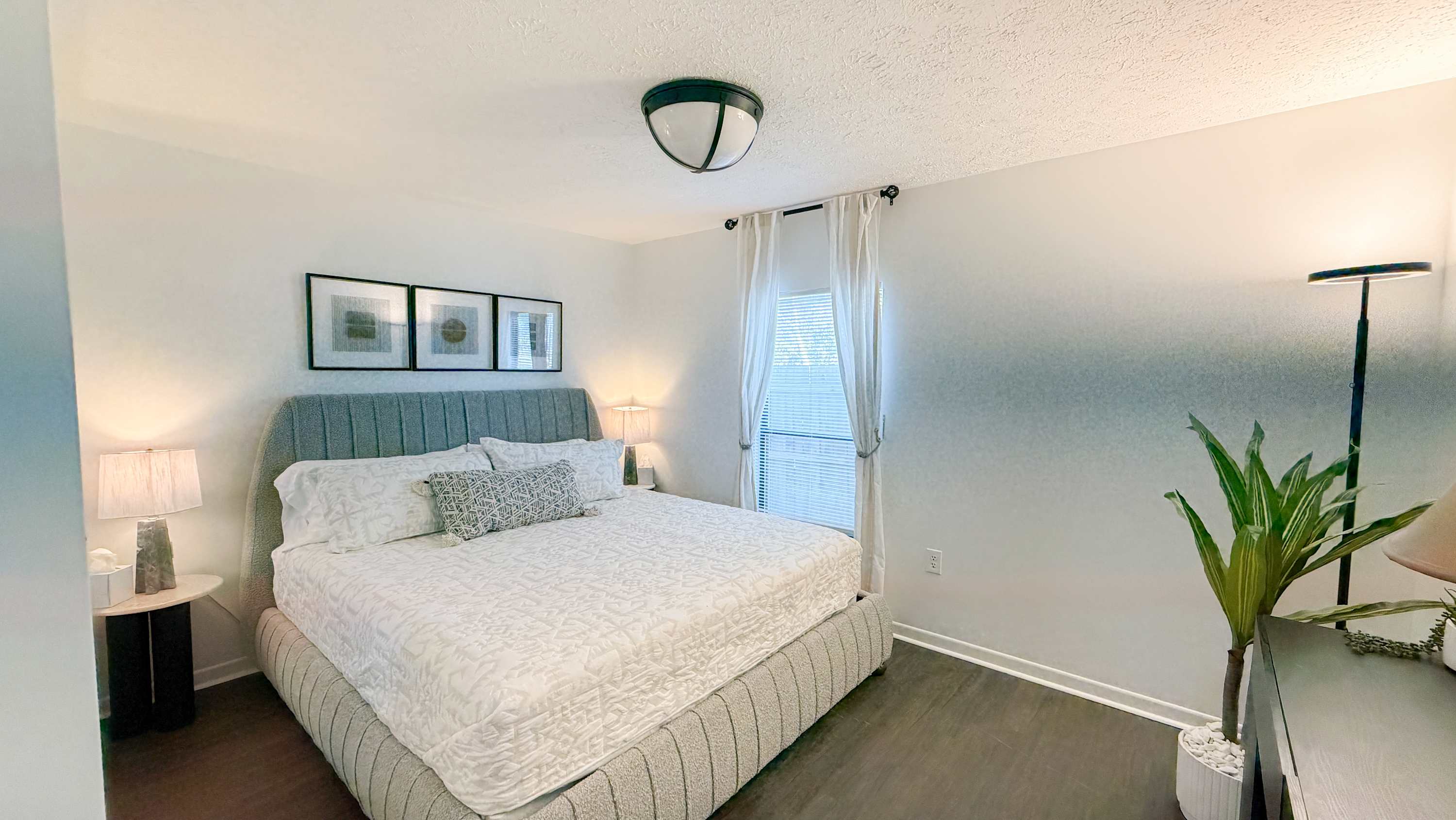 300 W 23rd Pl – Bright bedroom with a queen bed, lamp, window, and decorative plant.