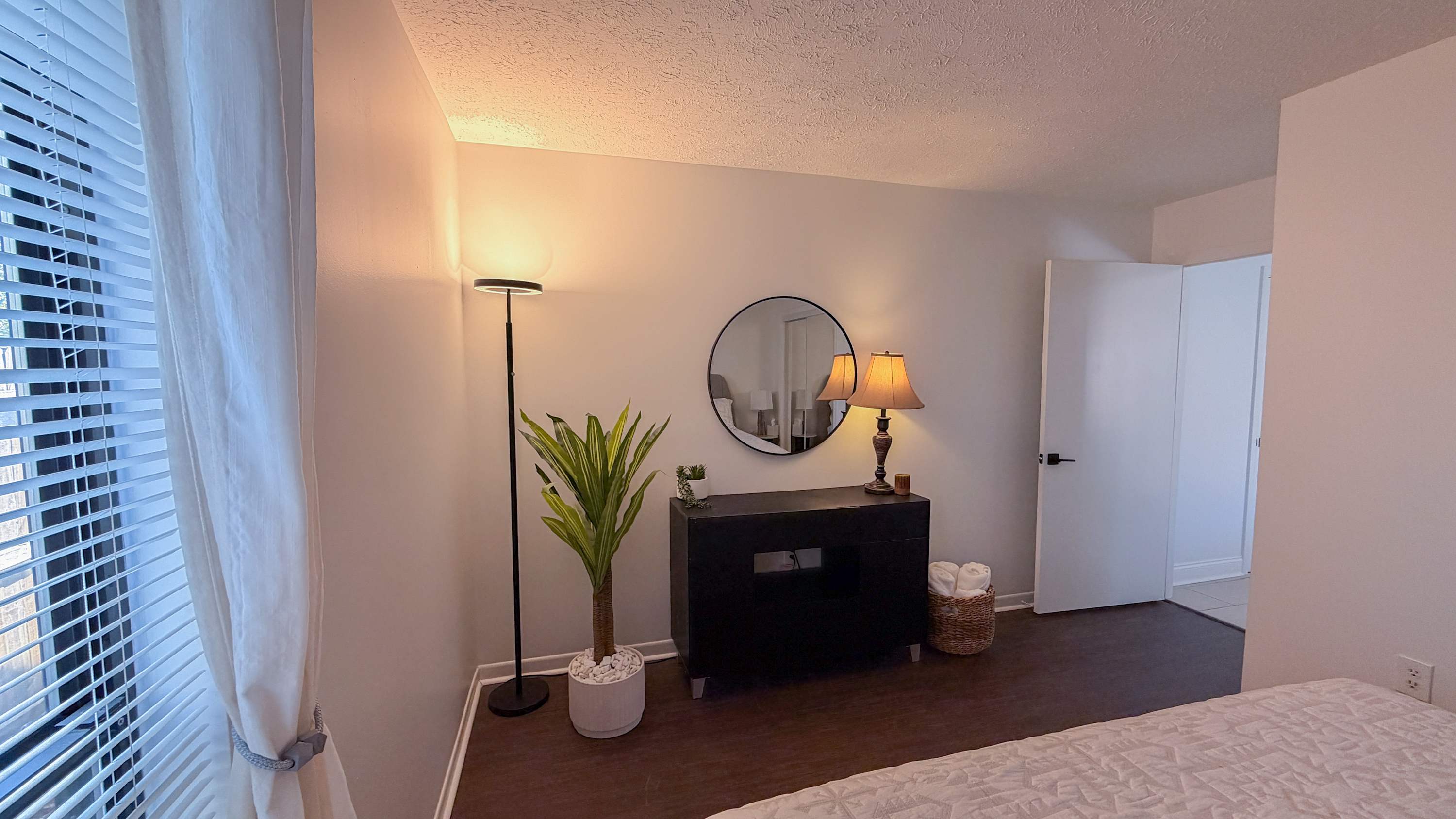 300 W 23rd Pl – Cozy bedroom with a dresser, lamp, plant, mirror, and door to a bathroom.